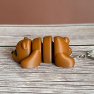 Side of a 3D printed brown bear-shaped keychain on a wooden surface
