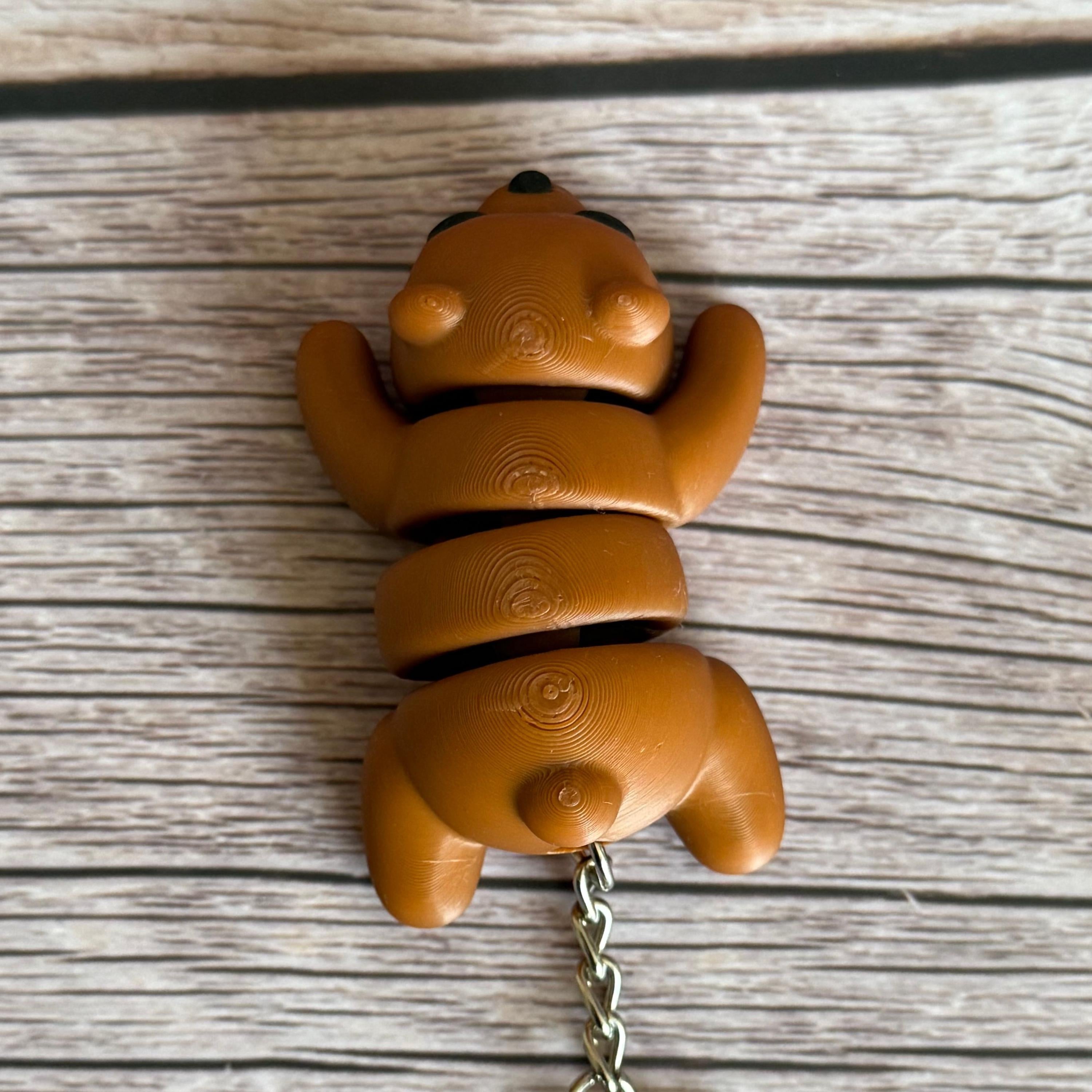 Top of a 3D printed brown bear-shaped keychain on a wooden surface