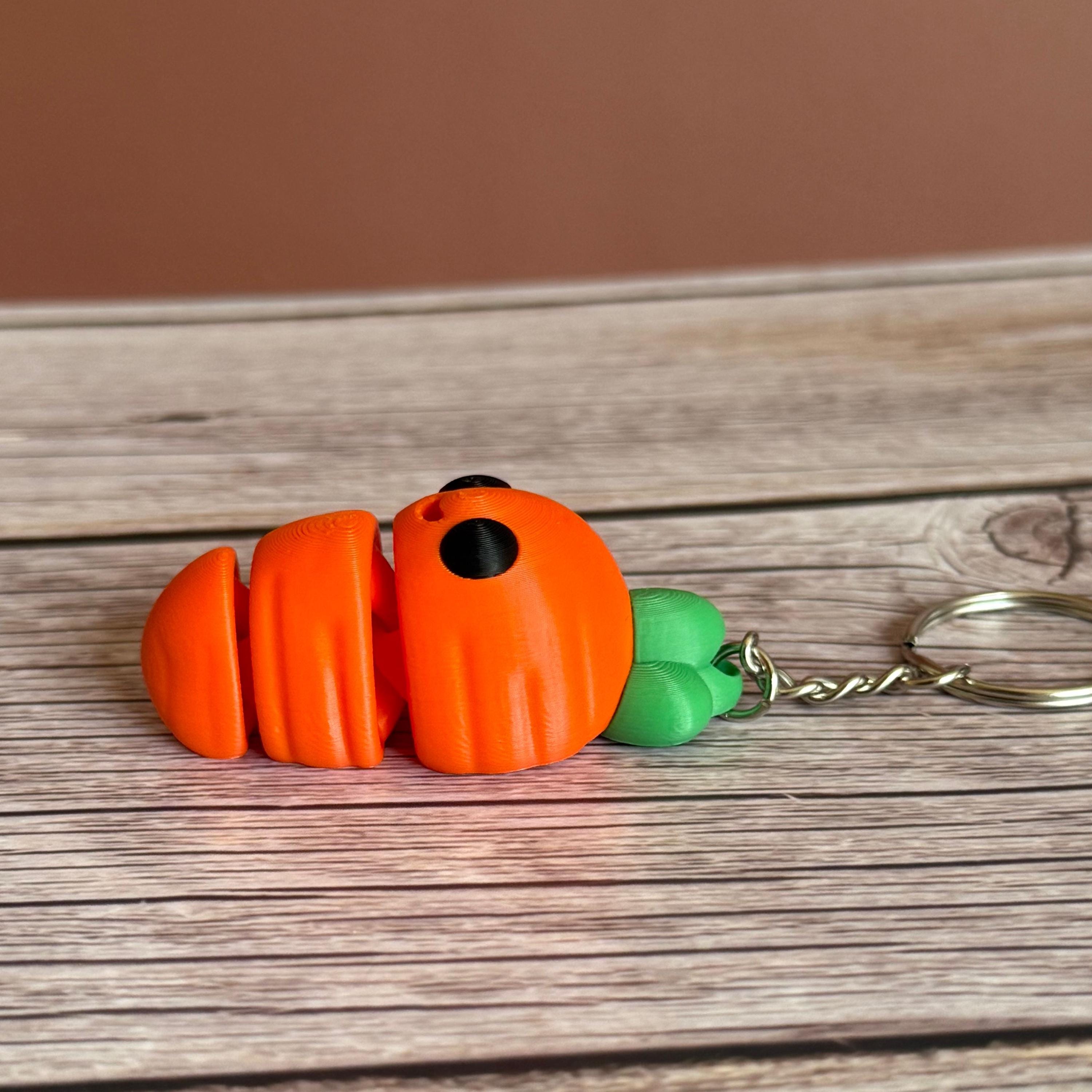 3D printed carrot-shaped keychain with a smiling face on a wooden surface