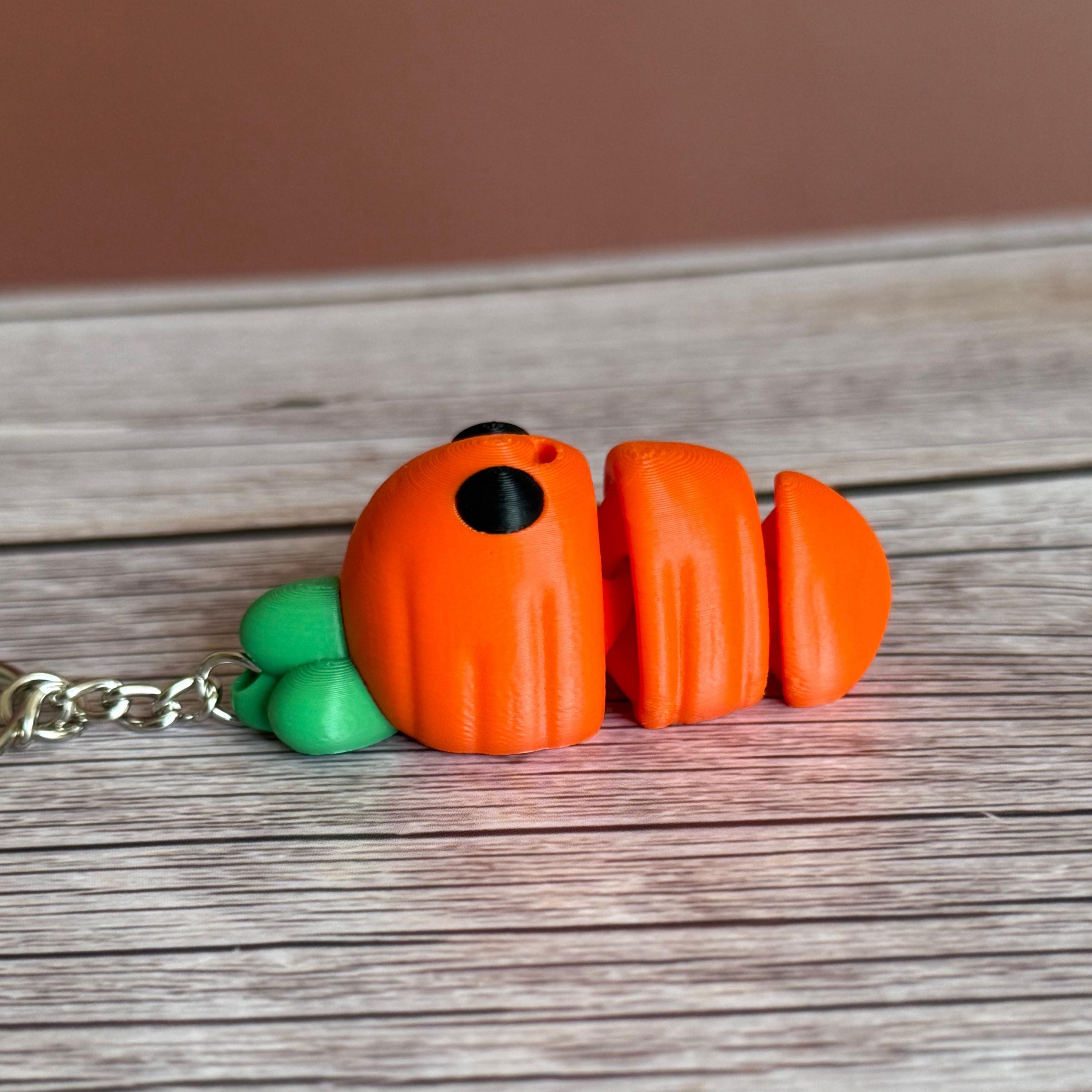 3D printed carrot-shaped keychain with a smiling face on a wooden surface