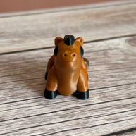 3D printed brown and black horse-shaped keychain on a wooden surface