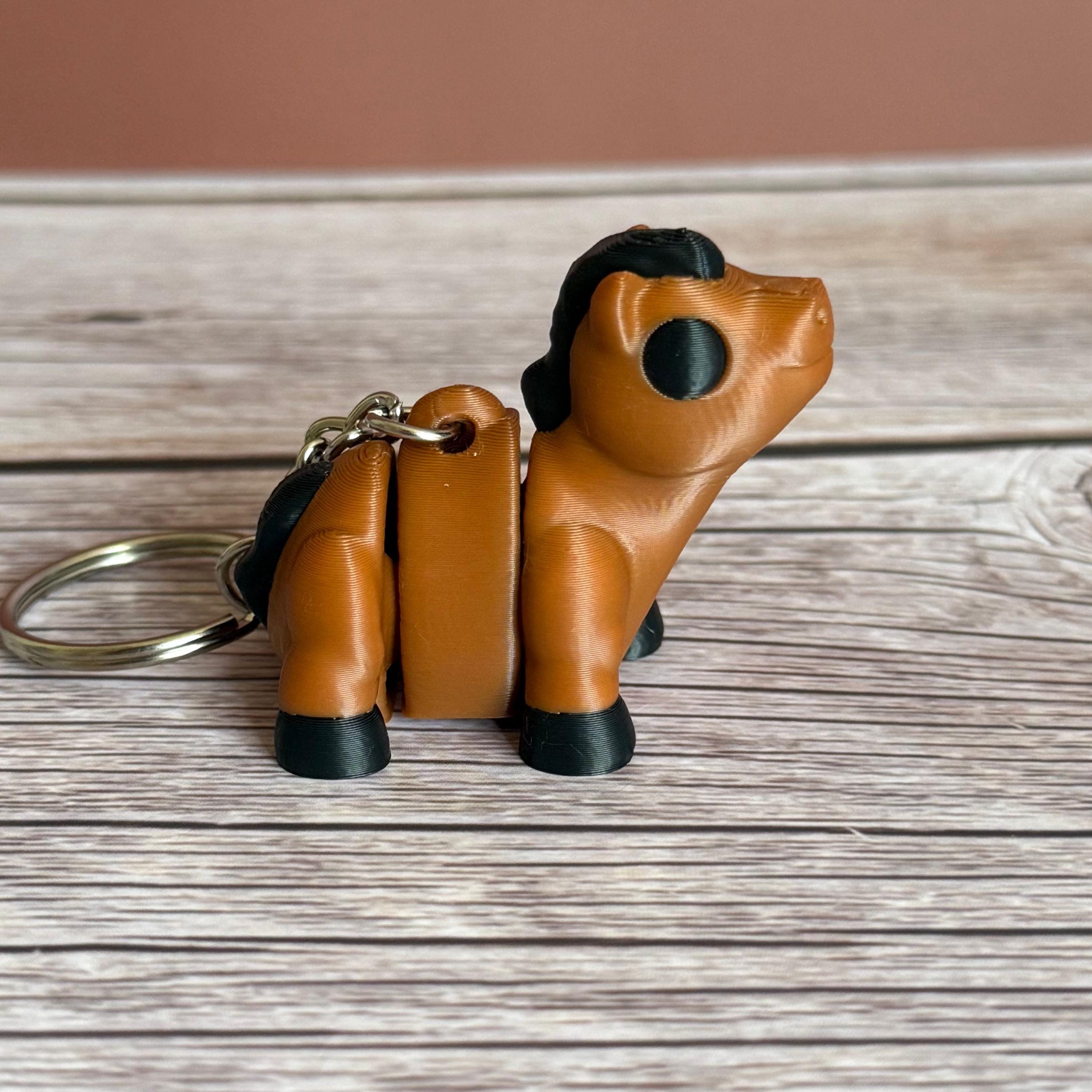 Side of a 3D printed brown and black horse-shaped keychain on a wooden surface