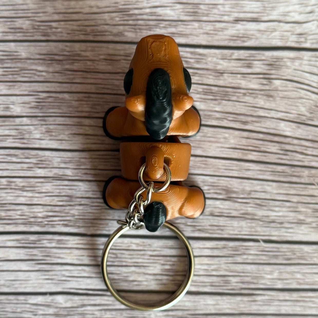 top of a 3D printed brown and black horse-shaped keychain on a wooden surface