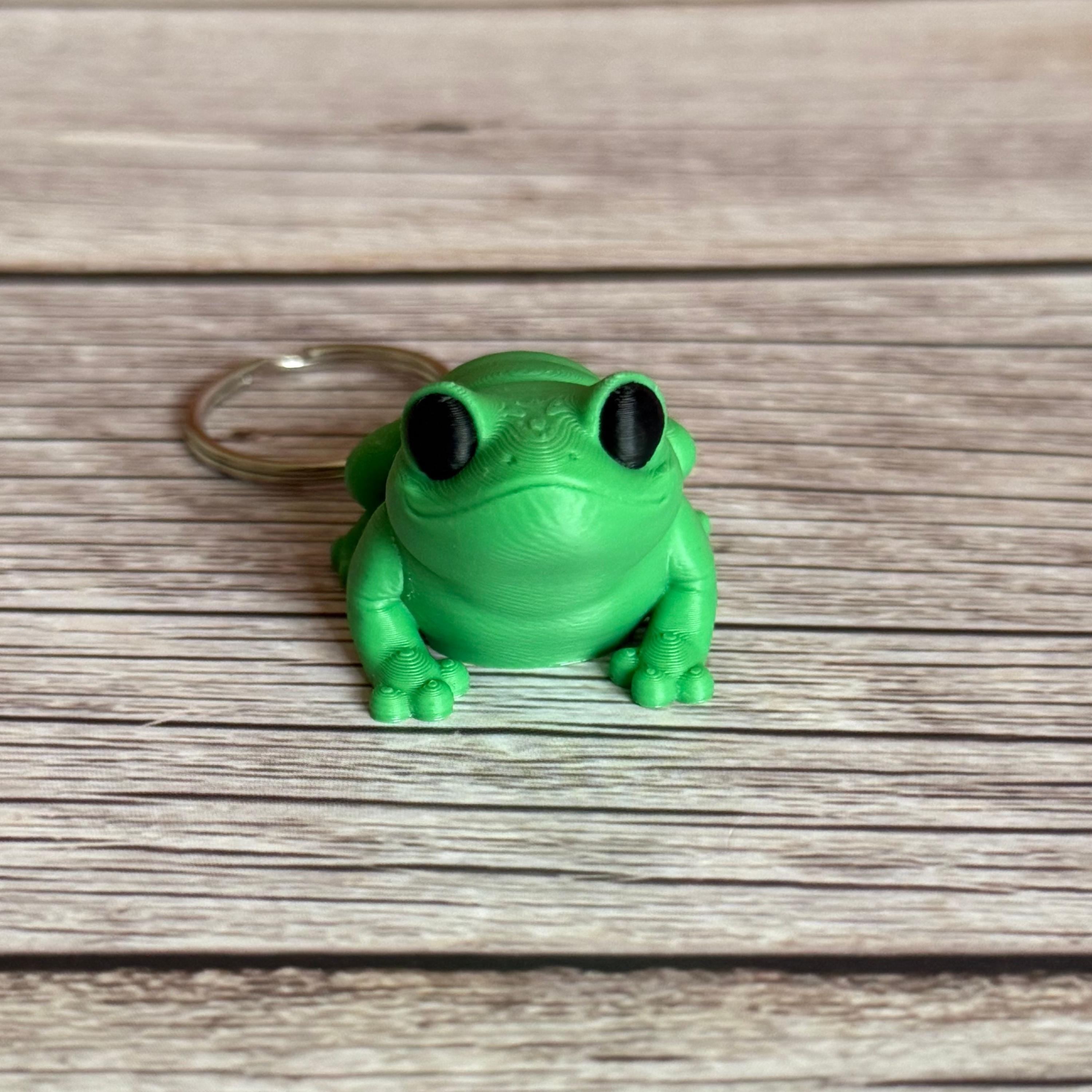 3D printed green frog-shaped keychain on a wooden surface
