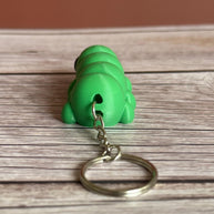 Back of a 3D printed green caterpillar-shaped keychain on a wooden surface