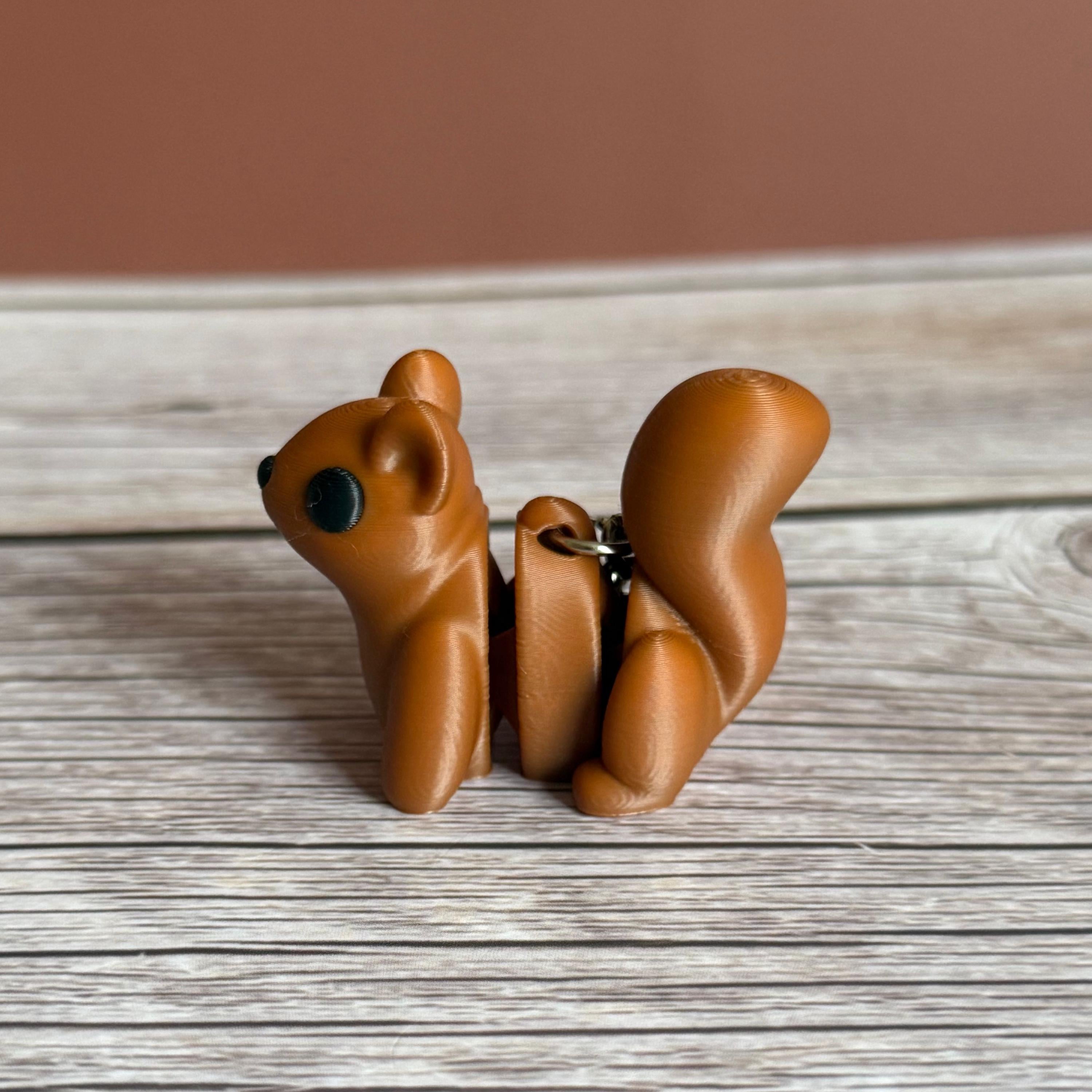 Side of a 3D printed brown squirrel-shaped keychain on a wooden surface