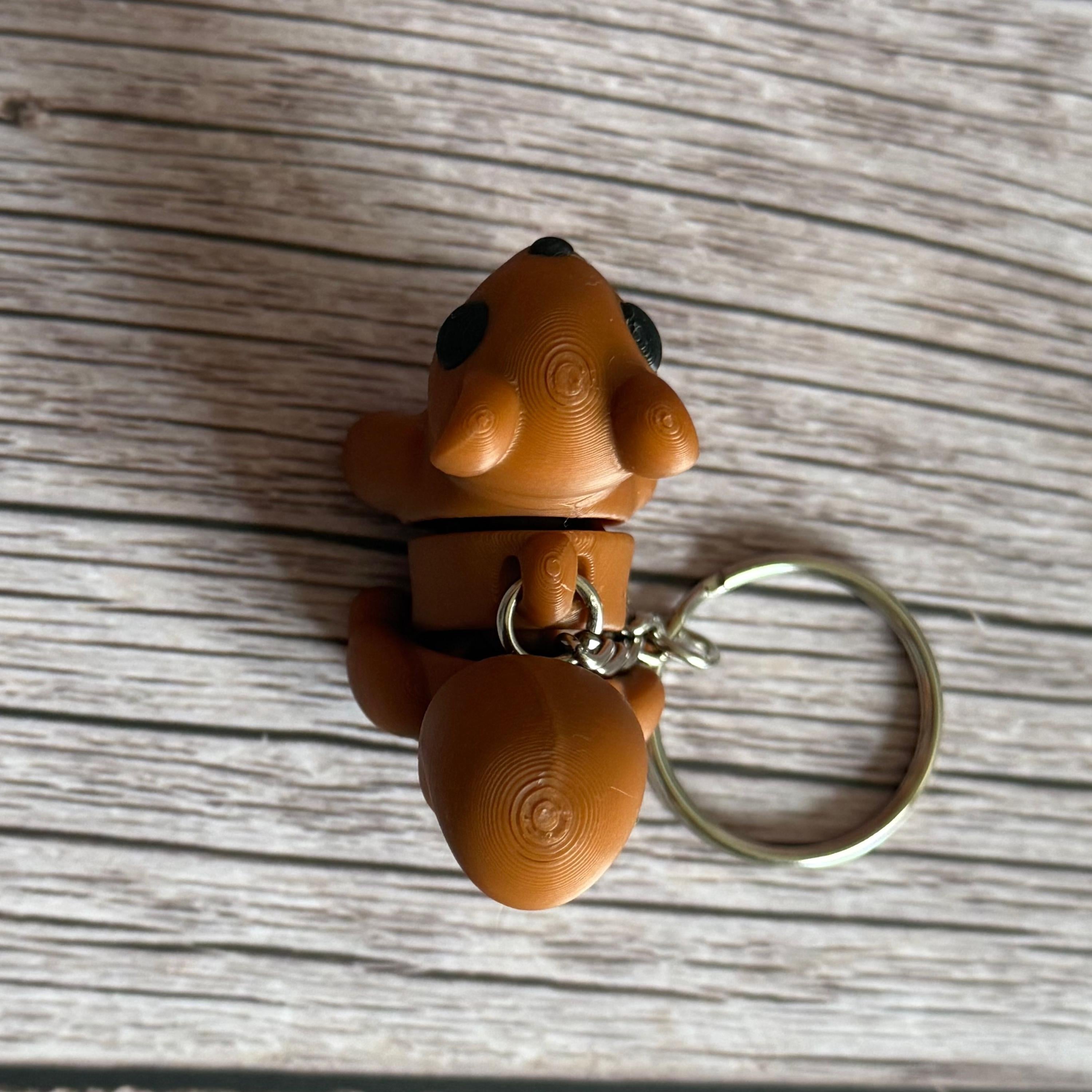 Top of a 3D printed brown squirrel-shaped keychain on a wooden surface