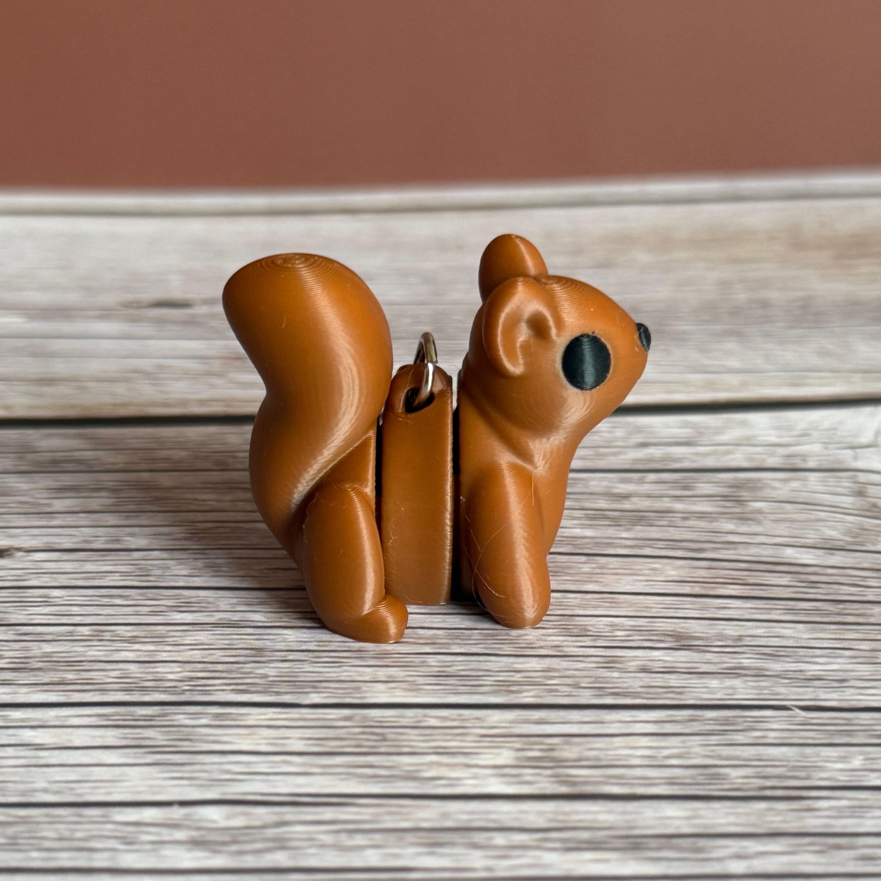 Side of a 3D printed brown squirrel-shaped keychain on a wooden surface
