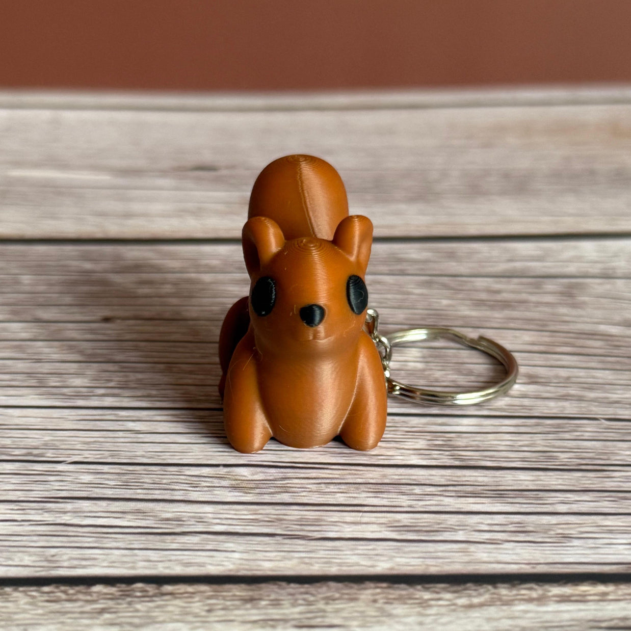 3D printed brown squirrel-shaped keychain on a wooden surface