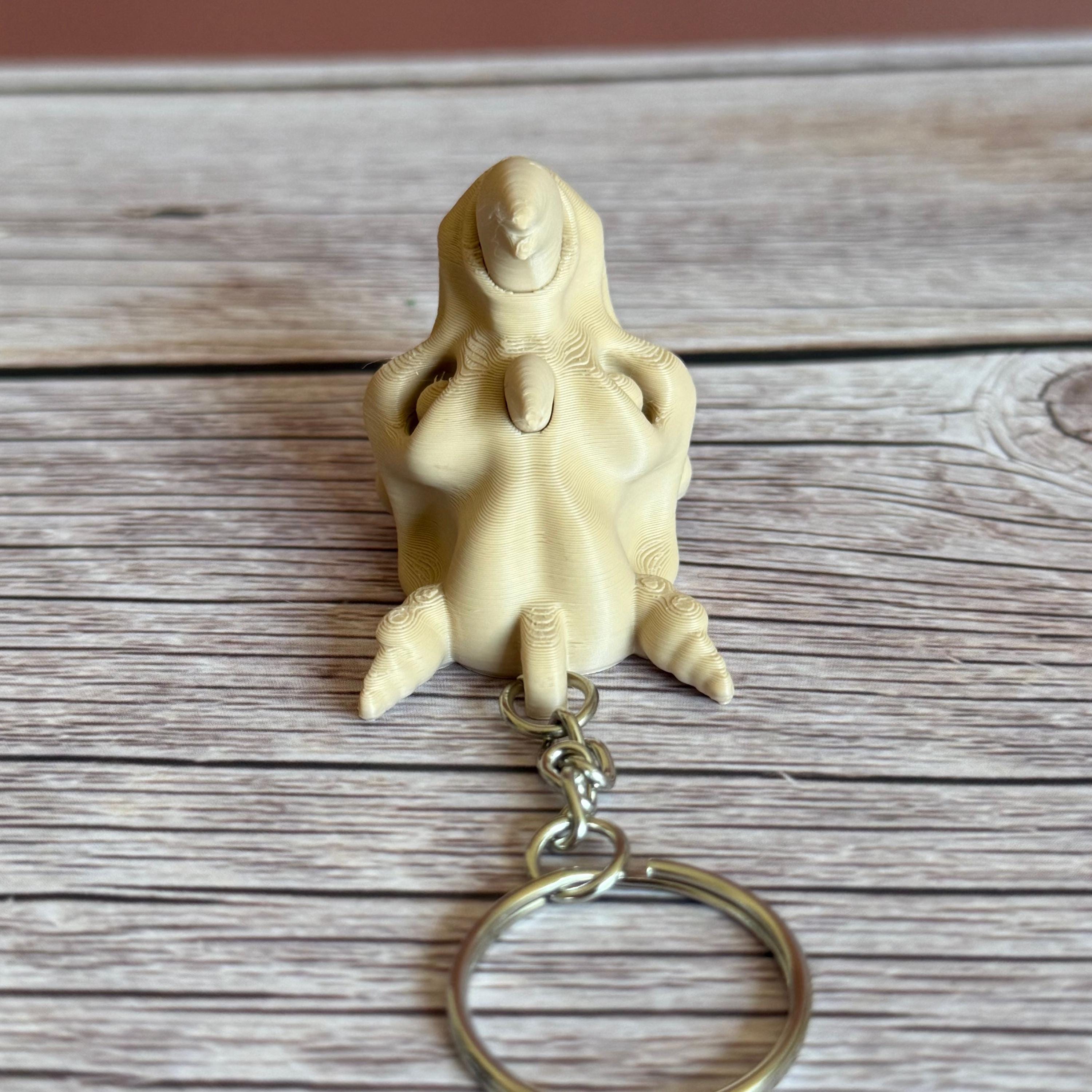 3D printed beige rhino skull keychain, placed on a wooden surface with a brown background