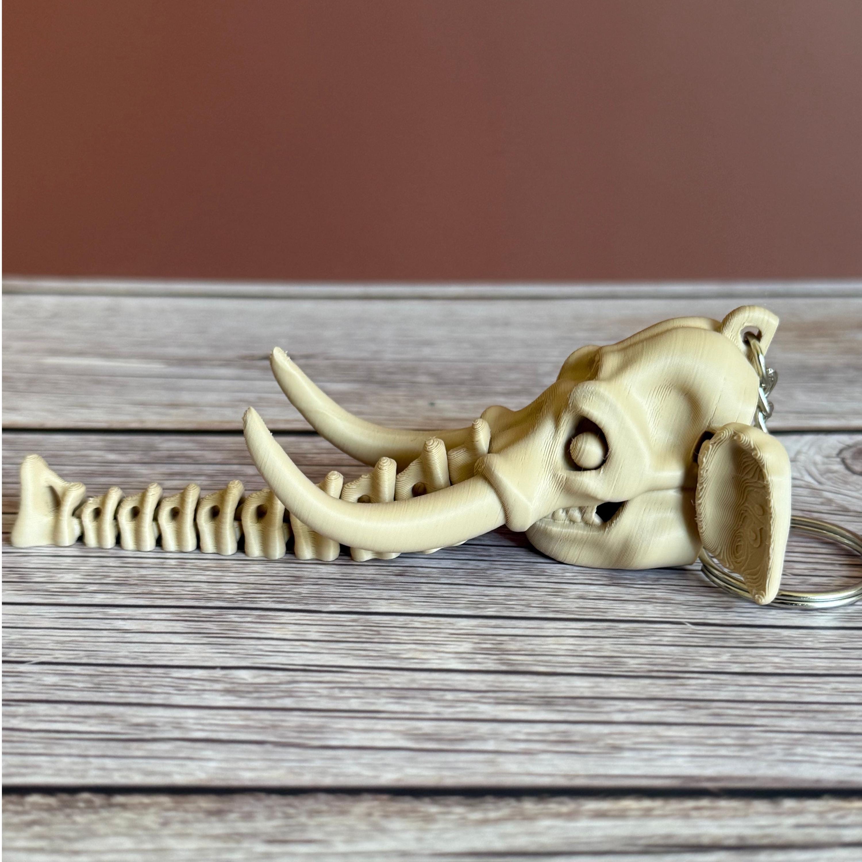 3D printed beige elephant skull with articulated skeleton-like trunk, placed on a wooden surface against a brown background