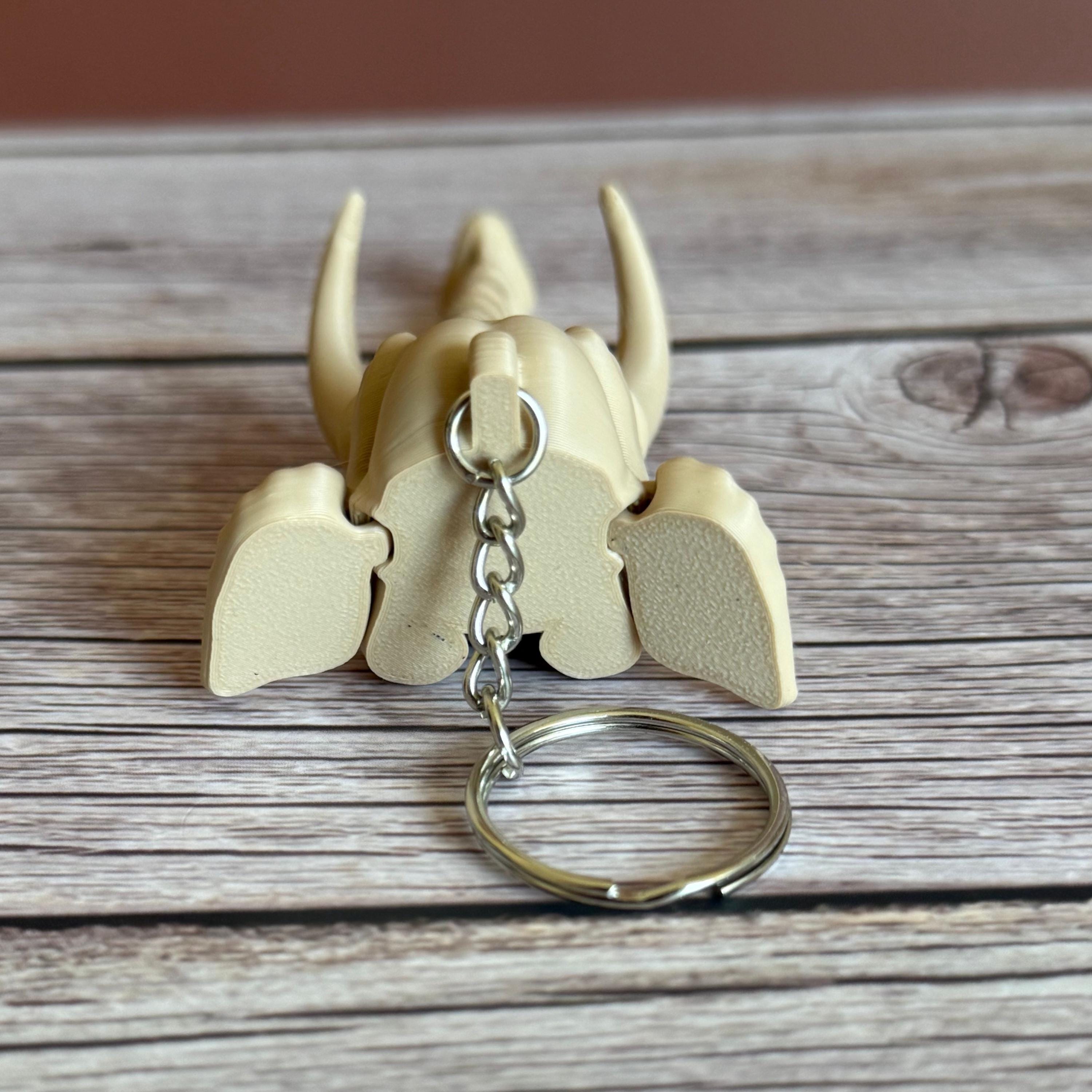 Back of 3D printed beige elephant skull with articulated skeleton-like trunk, placed on a wooden surface against a brown background