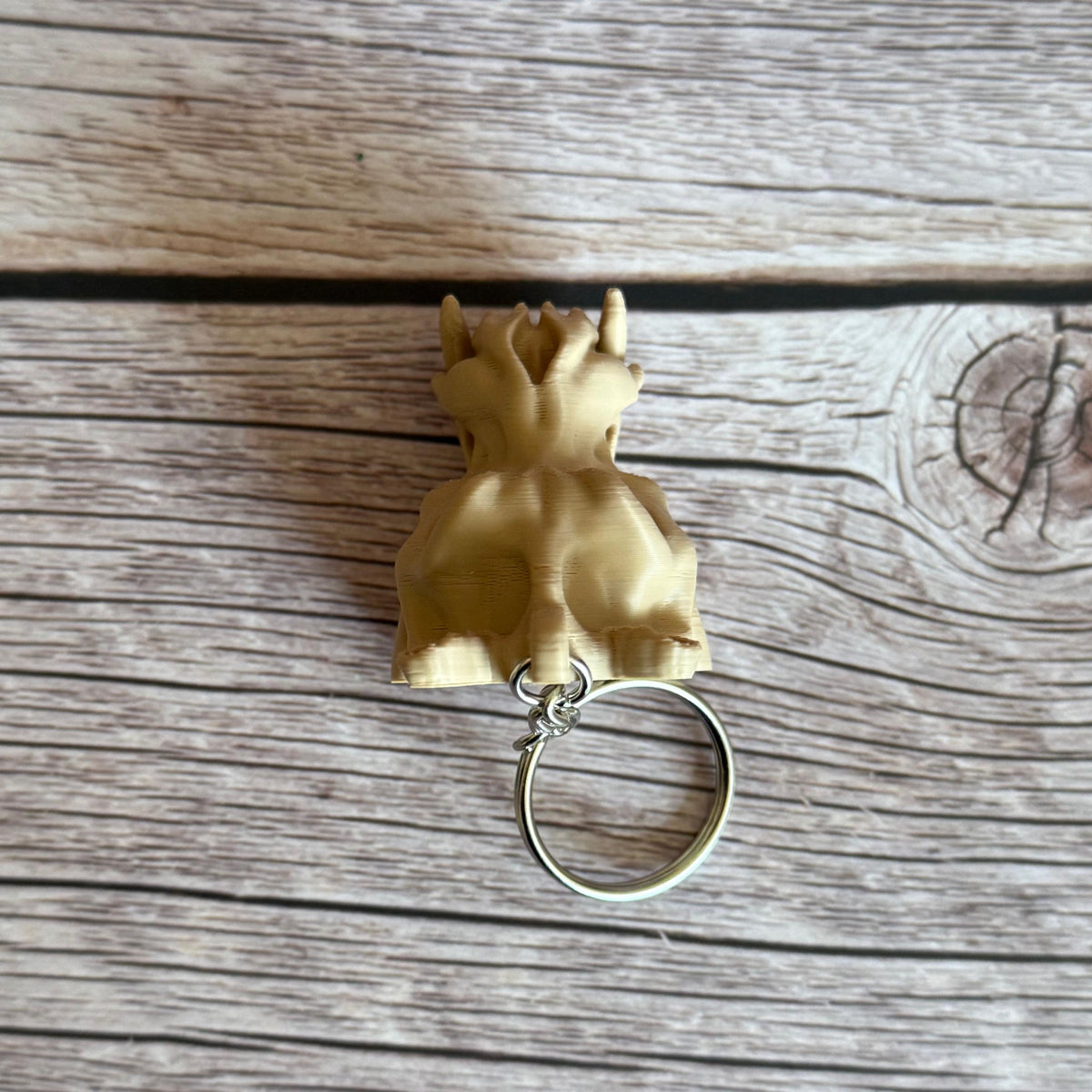 Top of 3D printed beige hippo skull keychain, placed on a wooden surface