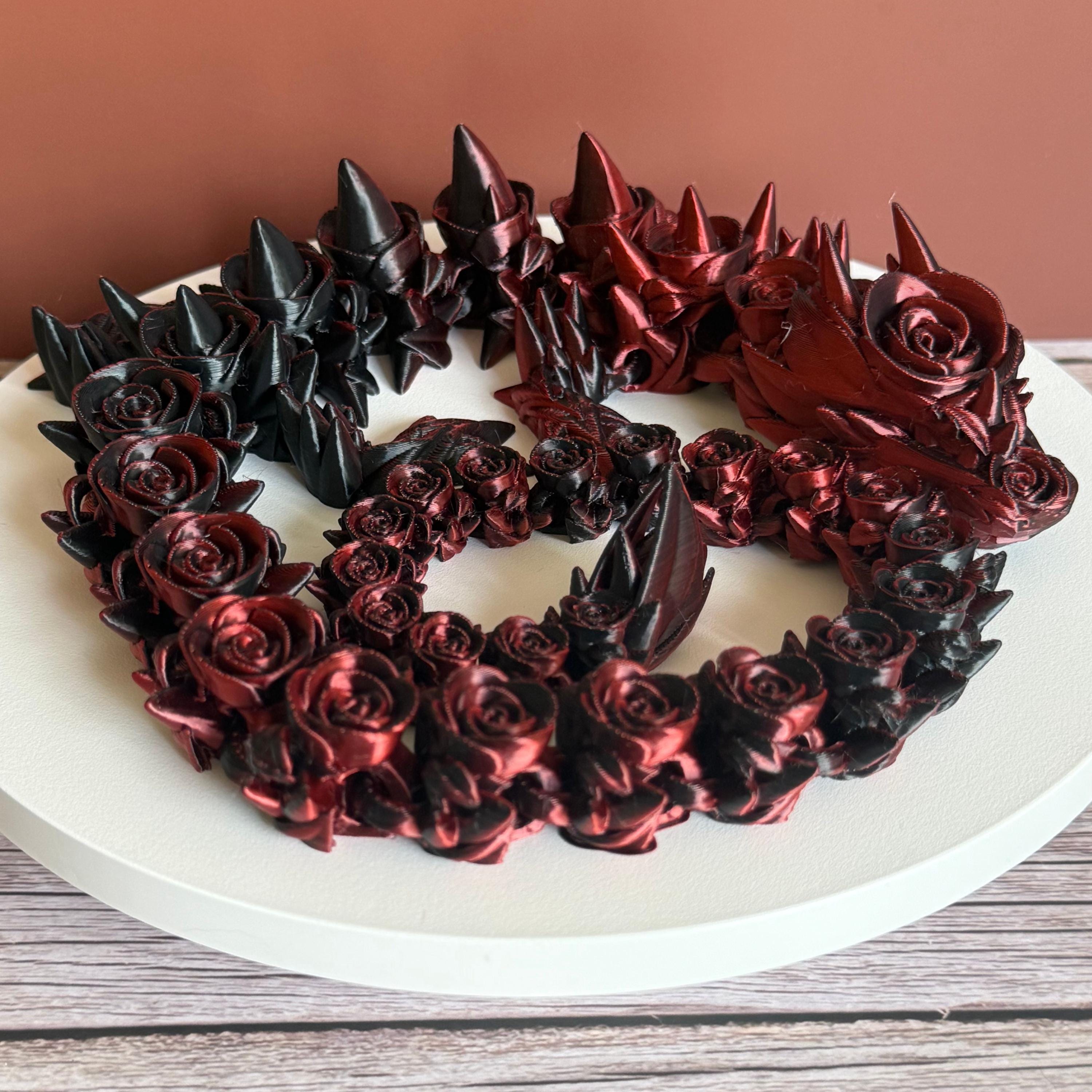 3D printed red and black dragon with rose and spike design on a white surface
