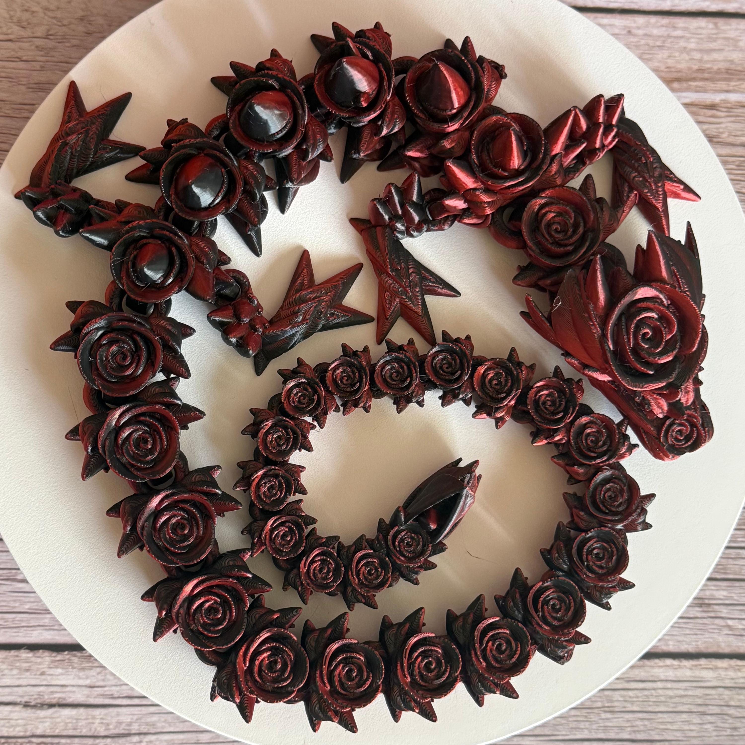 Top of 3D printed red and black dragon with rose and spike design on a white surface