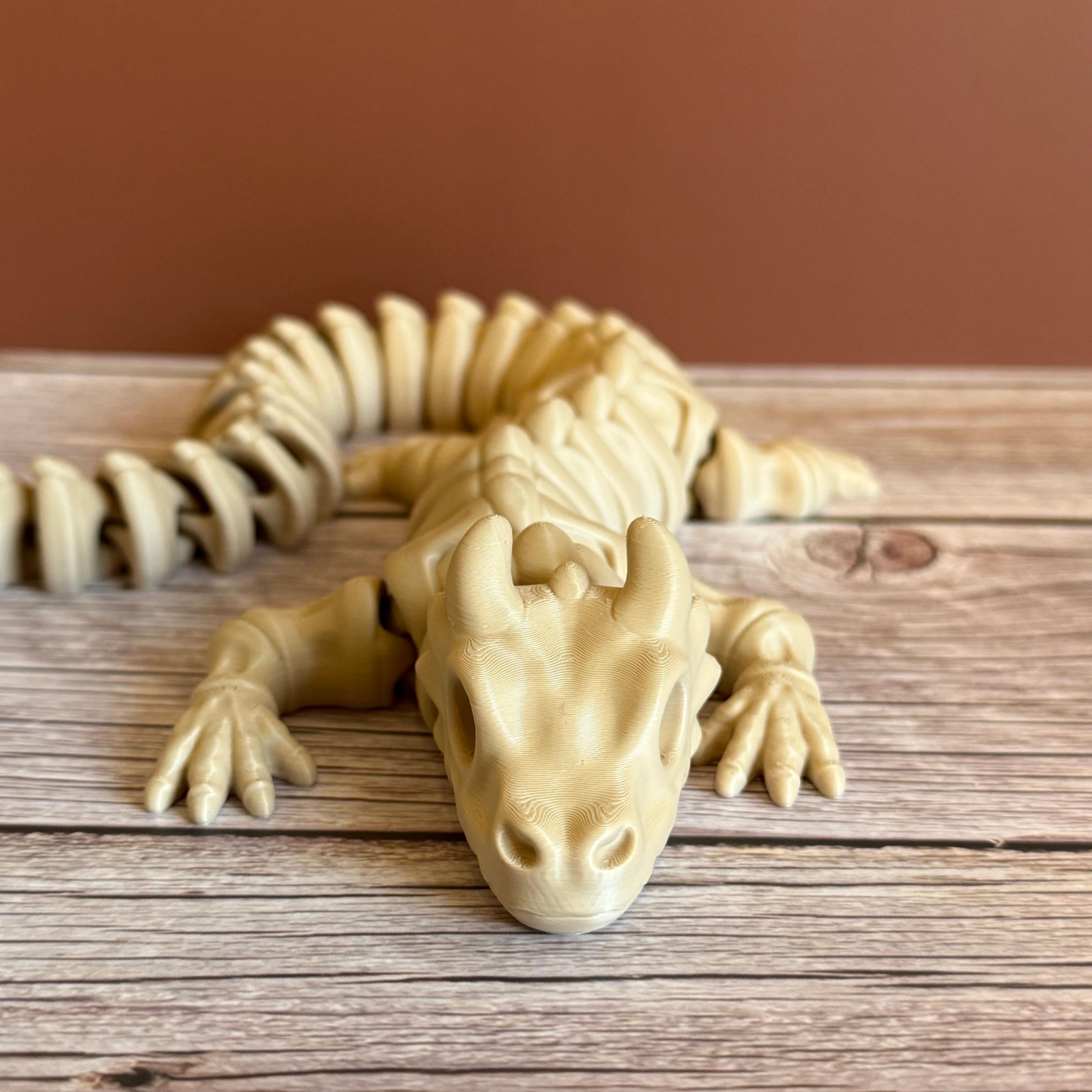 3D printed beige dragon skeleton toy, placed on a wooden surface