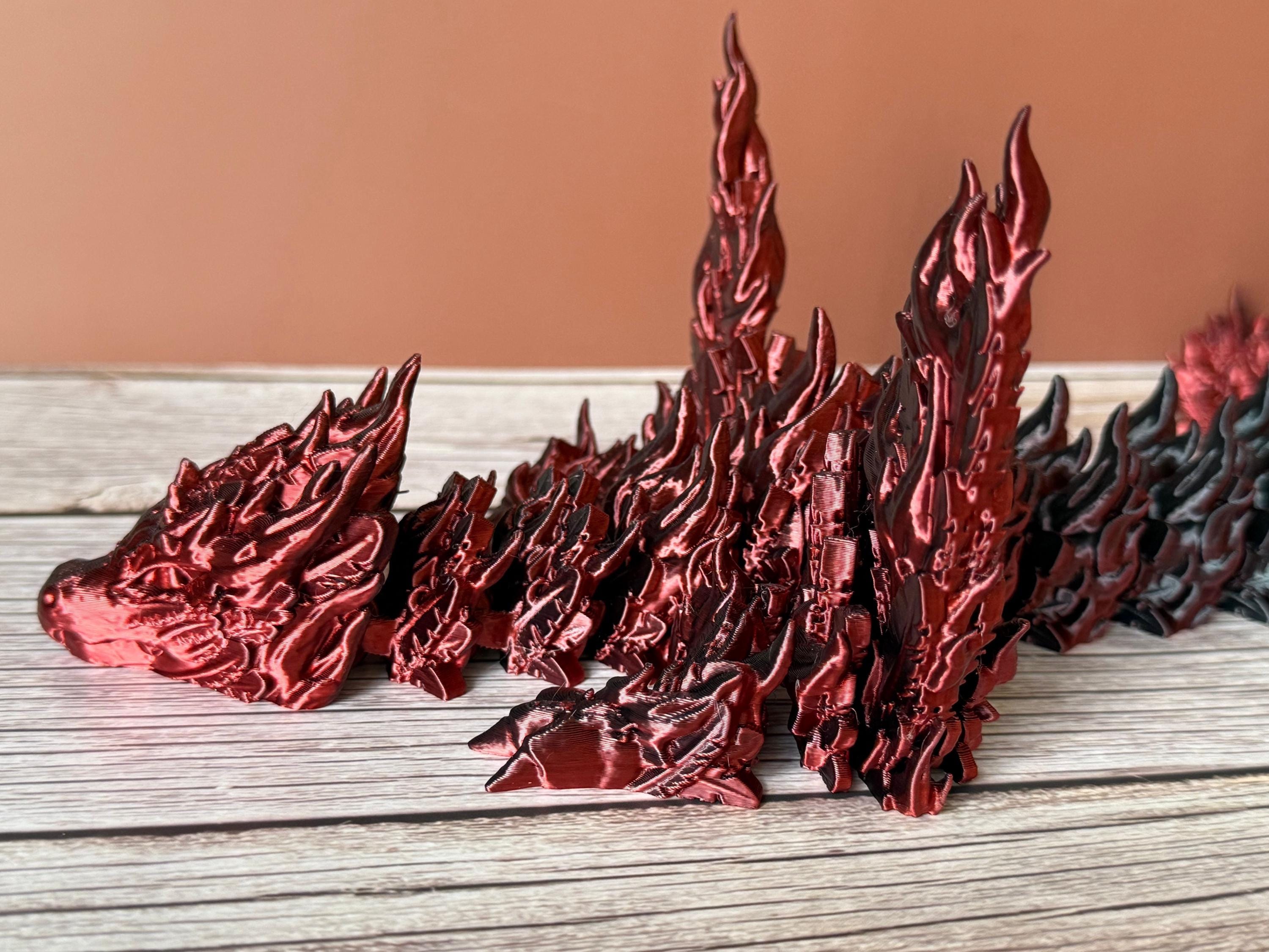 Side of a 3D printed red and black dragon with flame-like features and wings, placed on a wooden surface
