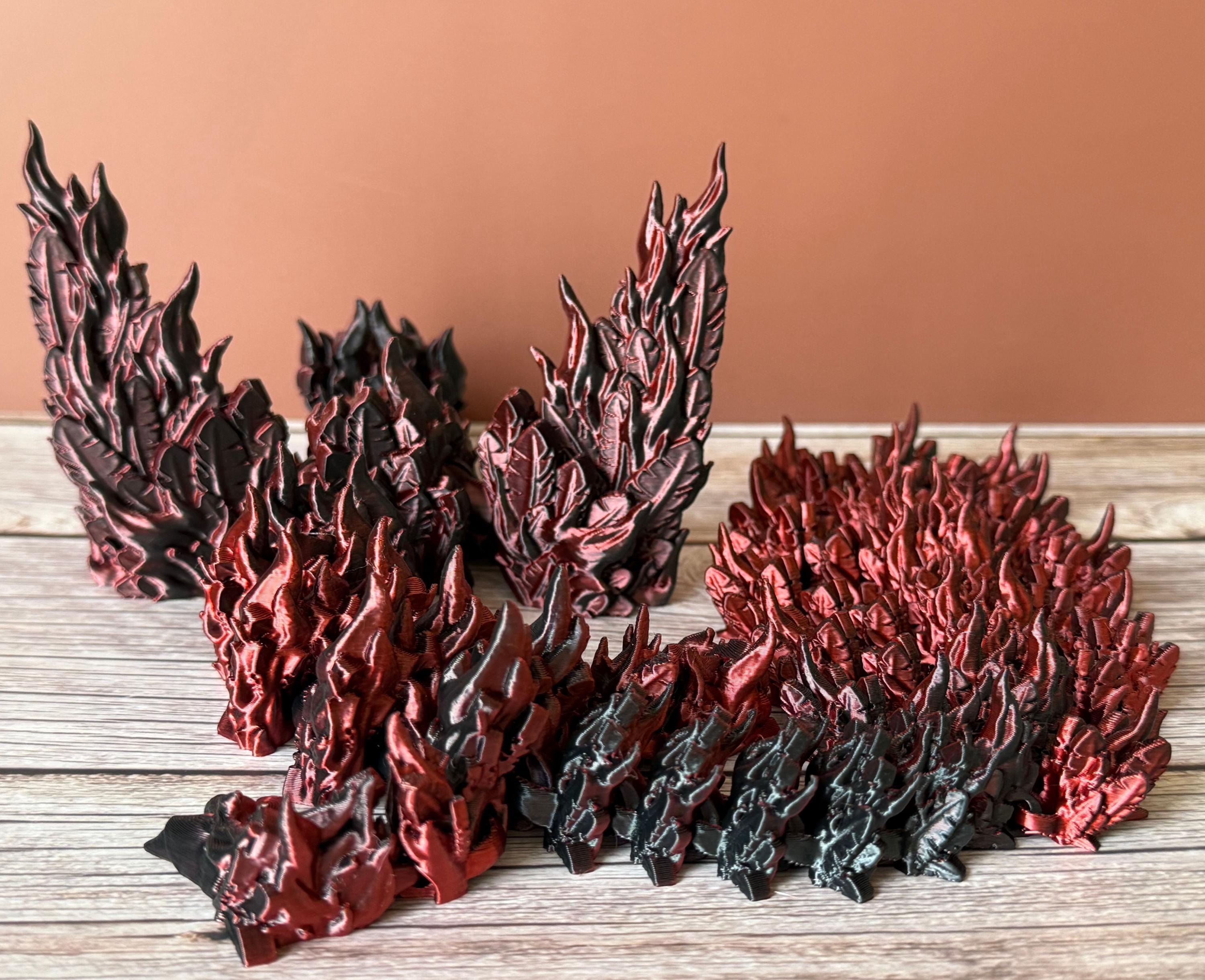 Back of a 3D printed red and black dragon with flame-like features and wings, placed on a wooden surface