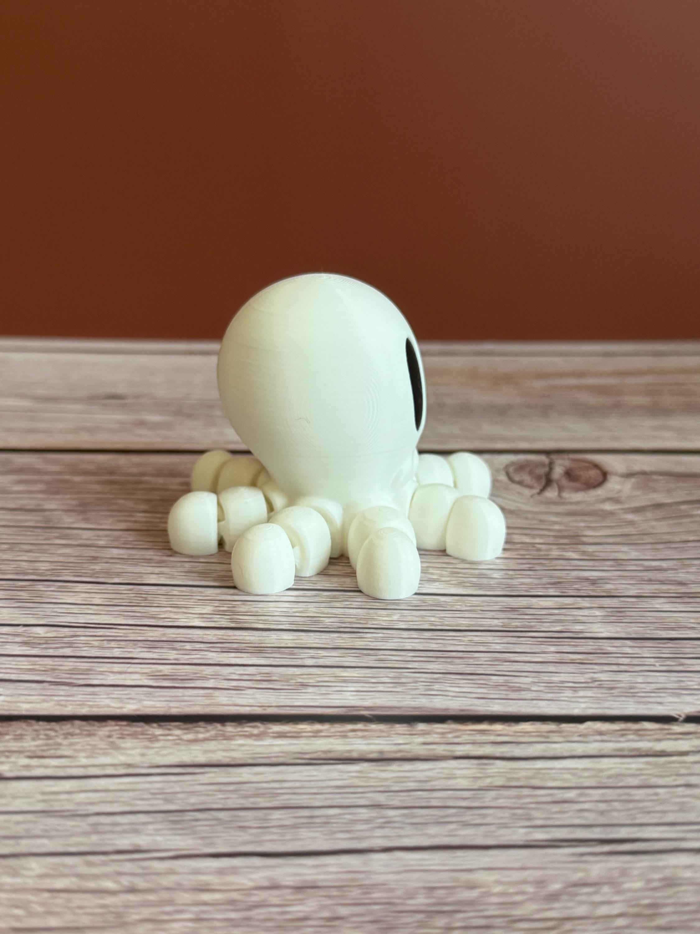 White 3D printed skeleton-like octopus placed on a wooden surface