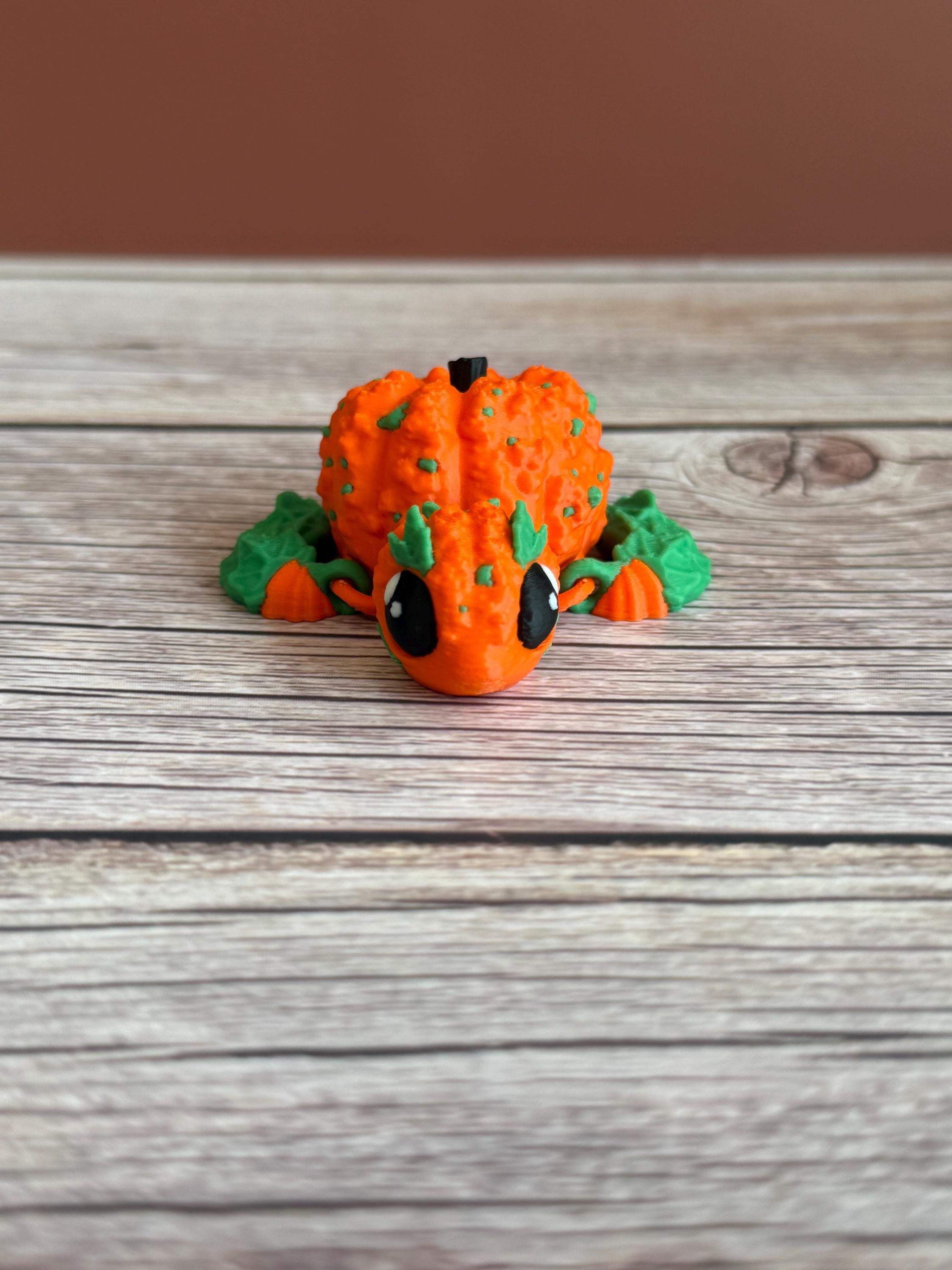 3D printed pumpkin-shaped turtle figure with leaf-like flippers, placed on a wooden surface