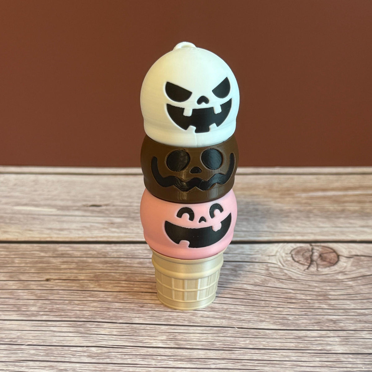 Pink, White, and Brown 3D printed ice cream cone keychain with smiling, mischievous, and goofy expressions on the ice cream scoops.