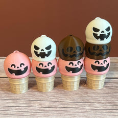 A collection of 3D printed ice cream cone keychains with various colorful designs, featuring expressions like smiling, goofy, and mischievous faces on the ice cream scoops.