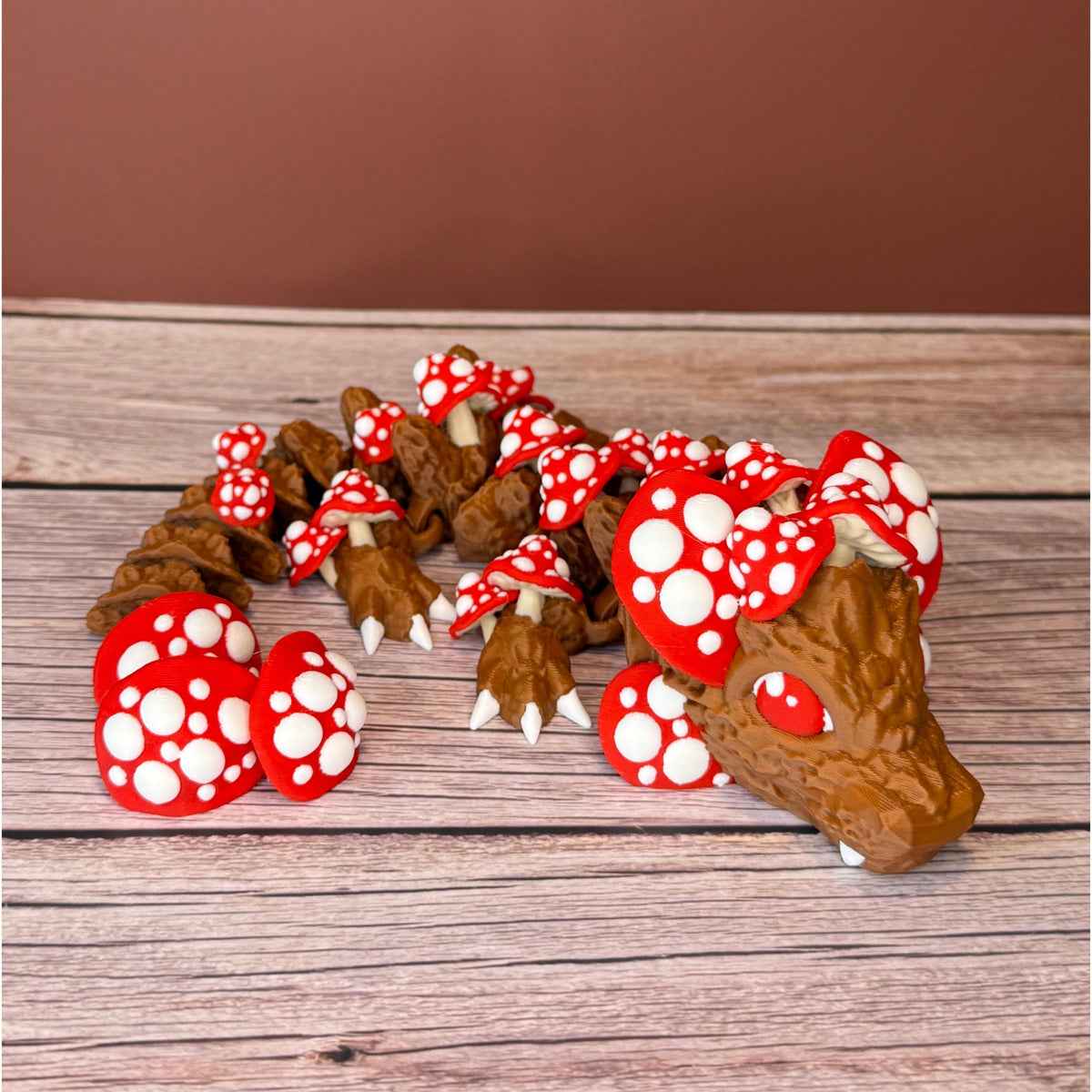A 12-inch articulated 3D printed dragon with a design resembling a mushroom, with red and white caps on a wooden surface.