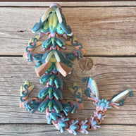 A 3D printed articulated fantasy creature resembling a dragon with butterfly features, in multicolor design, placed on a wooden surface