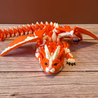 Orange and white 3D printed dragon figurine featuring a hybrid design of a dragon and a cat, placed on a wooden surface