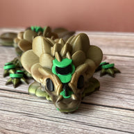 Brown and green 3D printed dragon figure with a clover shaped tail, placed on a wooden surface