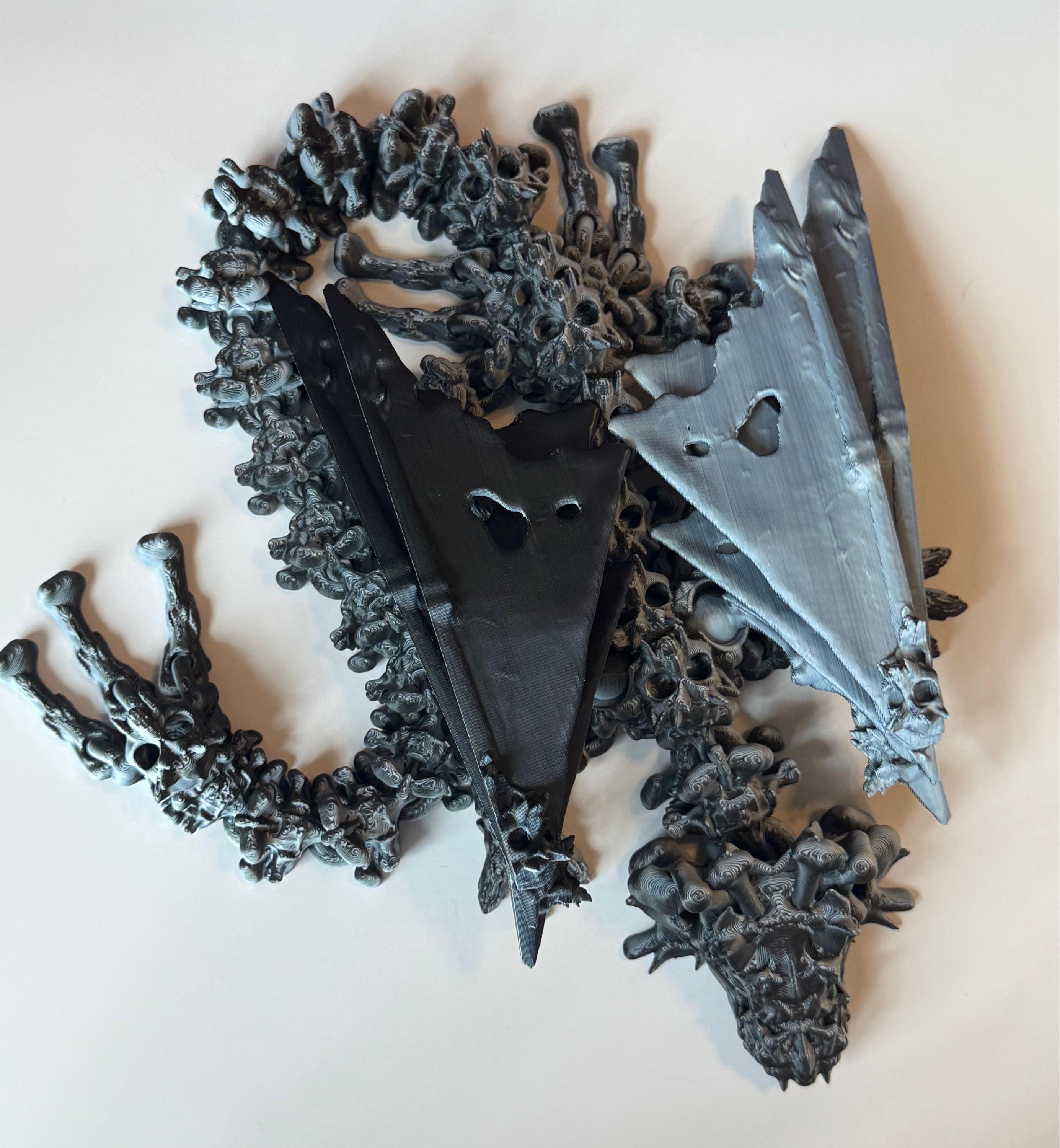 Winged black and white 3d printed dragon with a hollow theme consisting of skulls and bone-like features against a white background