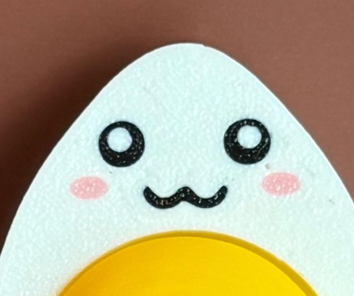 hard-boiled egg keychain with smiling face and cartoonish mouth design on a brown background