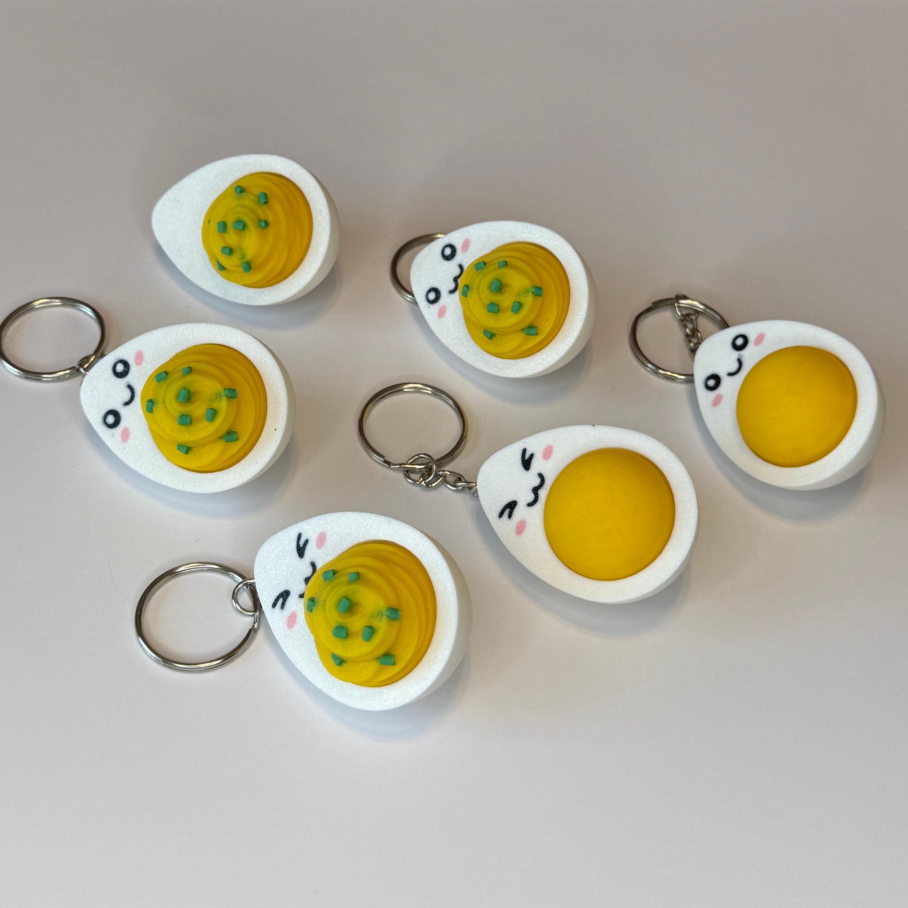 Set of hard-boiled egg and deviled egg keychains with cartoonish designs on a white background