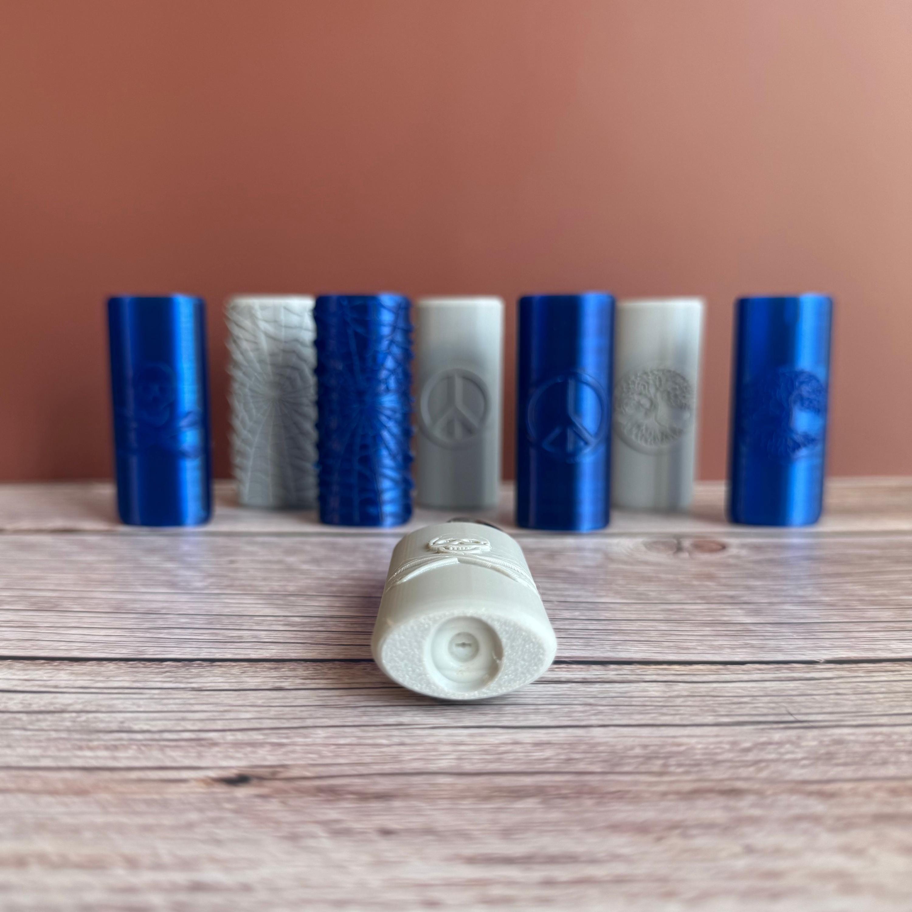 A collection of 3D printed Bic lighter cases with various designs such as Spider Web, Skull and Crossbones, Tree of Life, and Peace Sign, displayed in blue and gray colors.