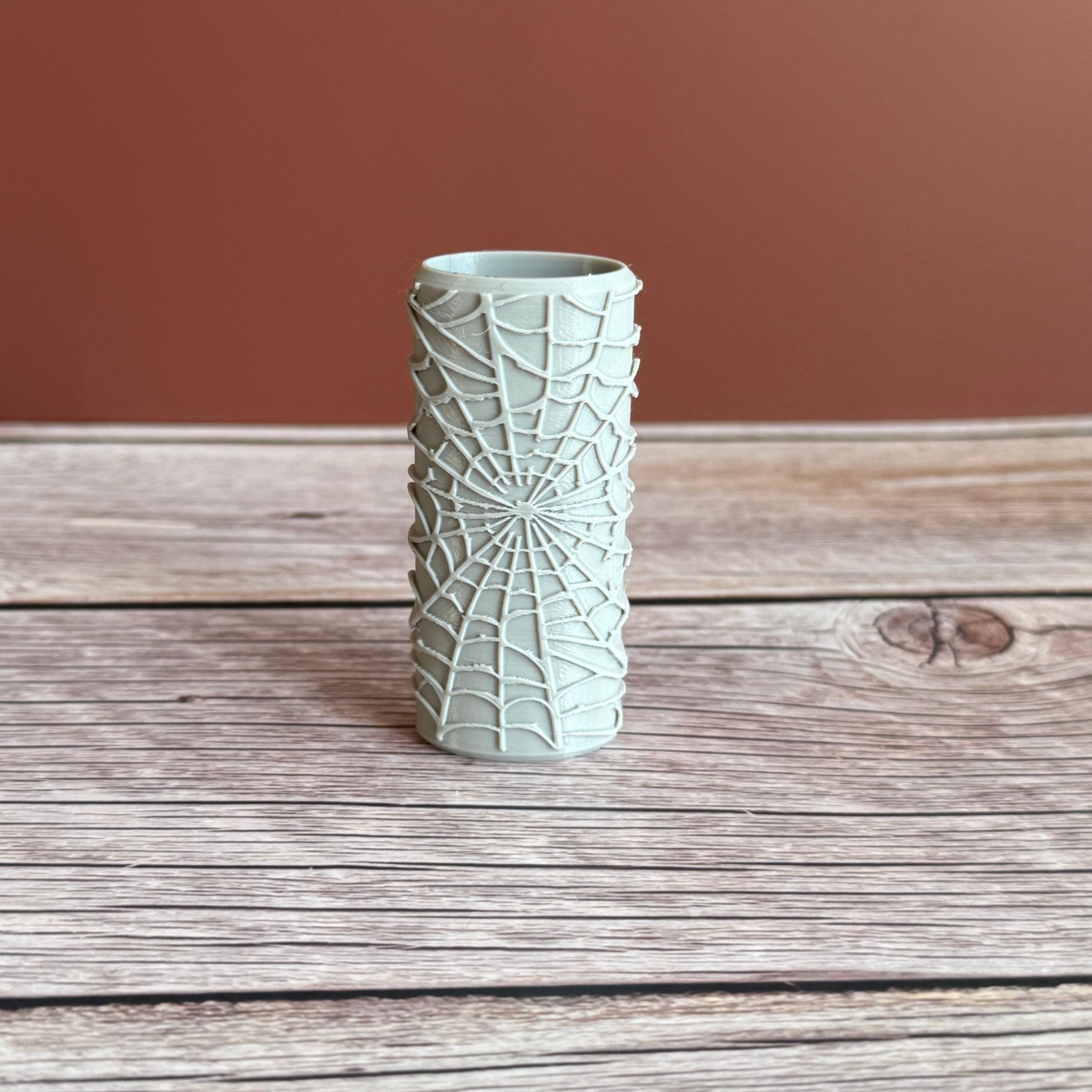 A 3D printed Bic lighter case with Spiderweb design displayed in gray color on wooden surface and brown background