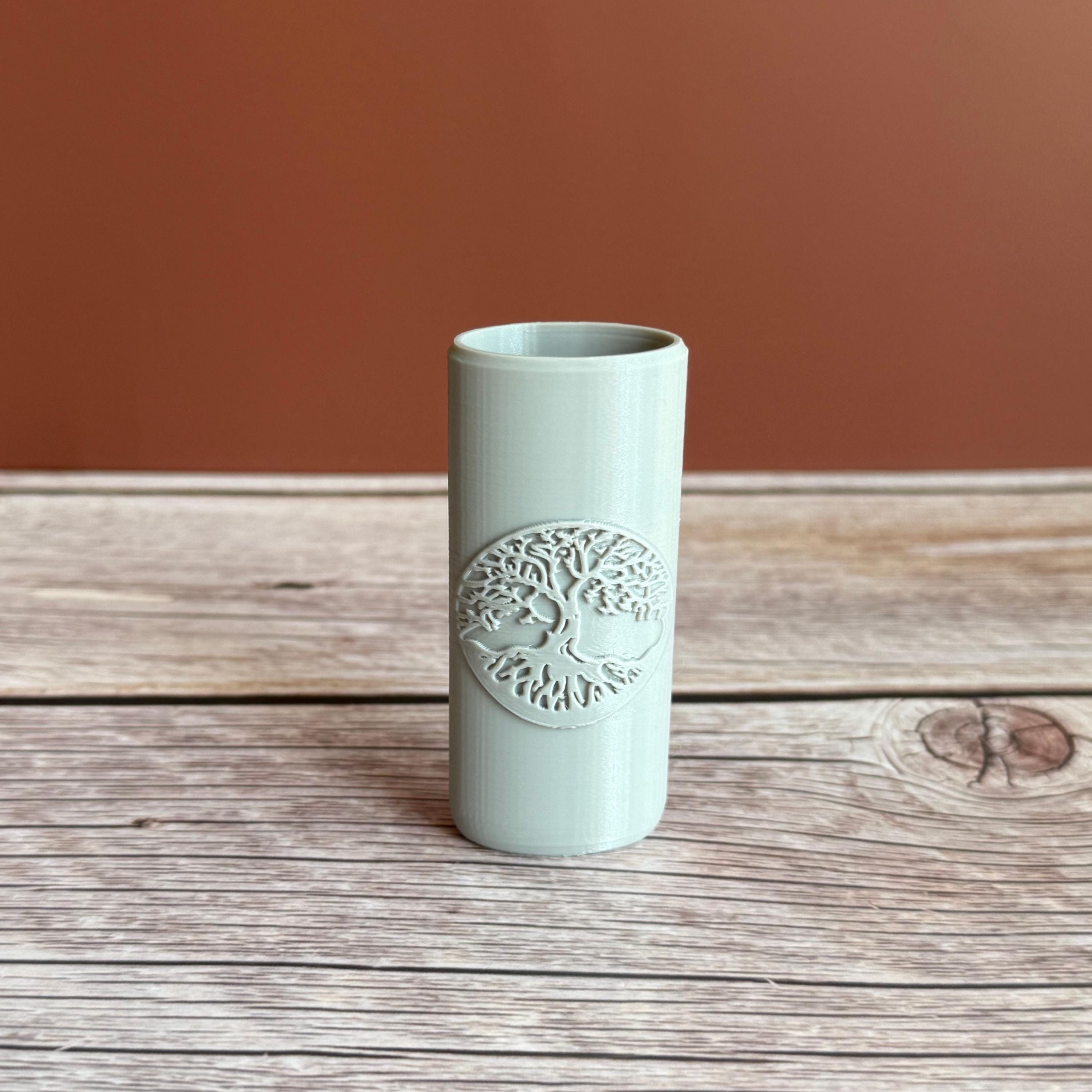 A 3D printed Bic lighter case with Tree of Life design displayed in gray color on wooden surface and brown background