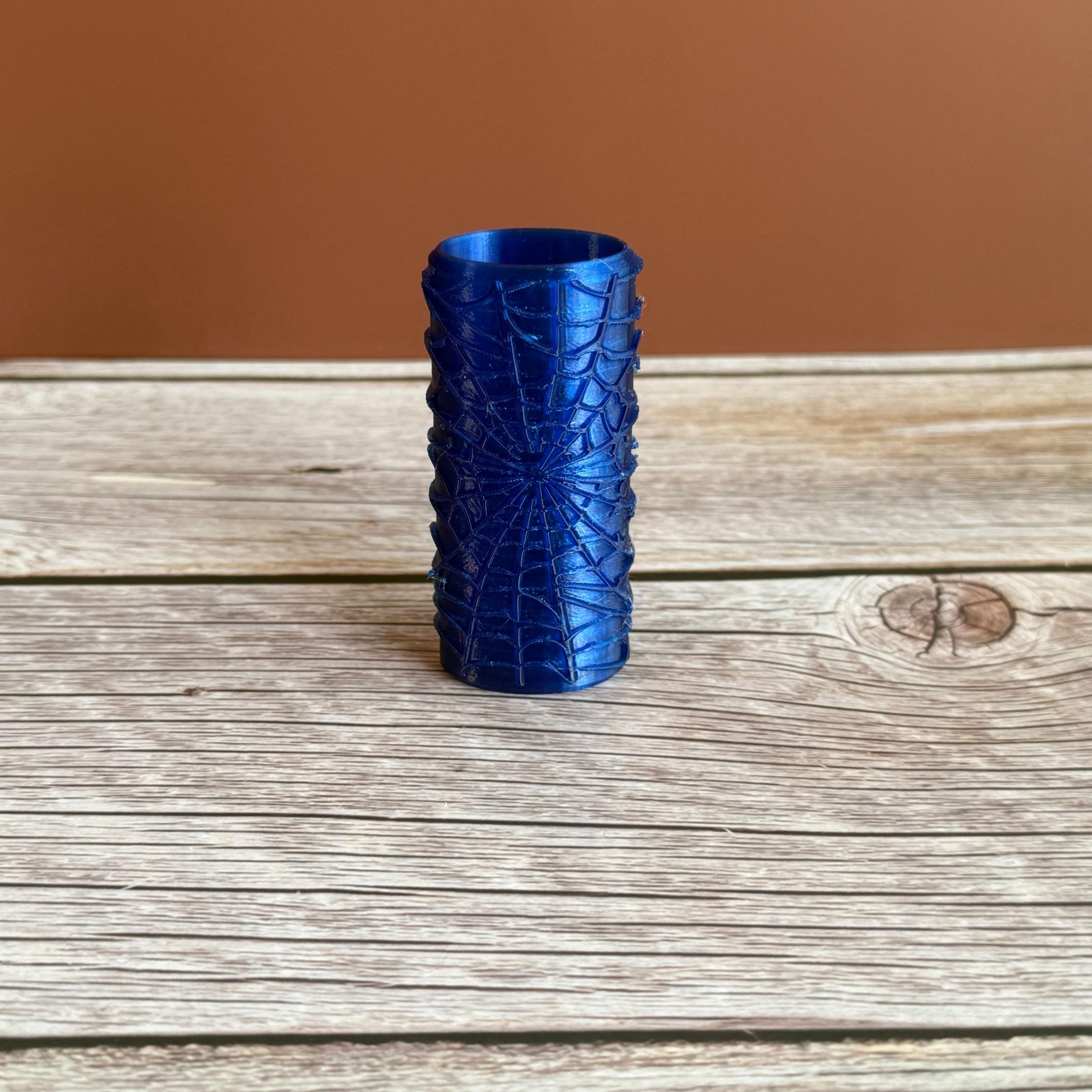 A 3D printed Bic lighter case with Spiderweb design displayed in blue color on wooden surface and brown background