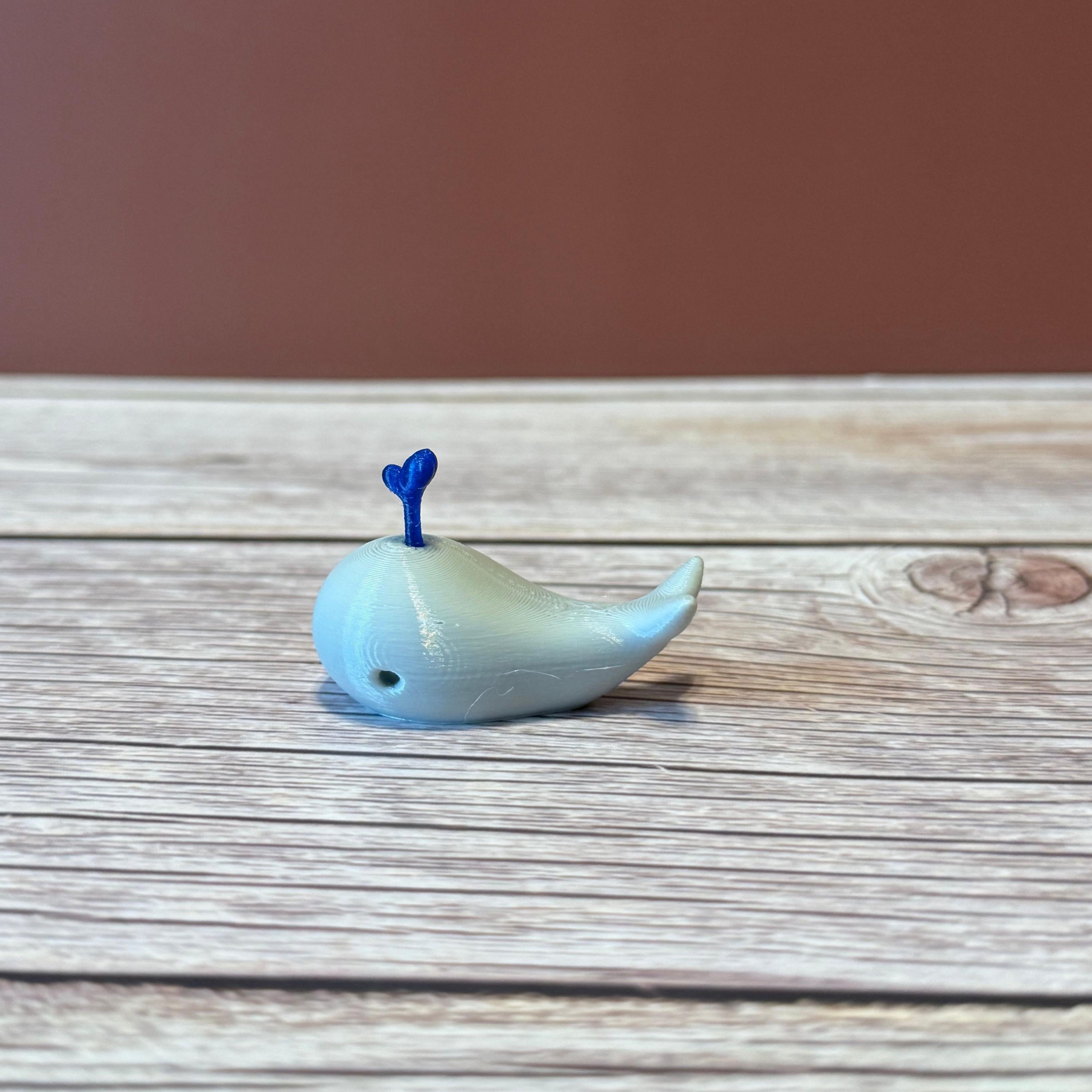 A 3D printed white whale chopstick rest with a space for holding chopsticks, placed on a wooden surface.