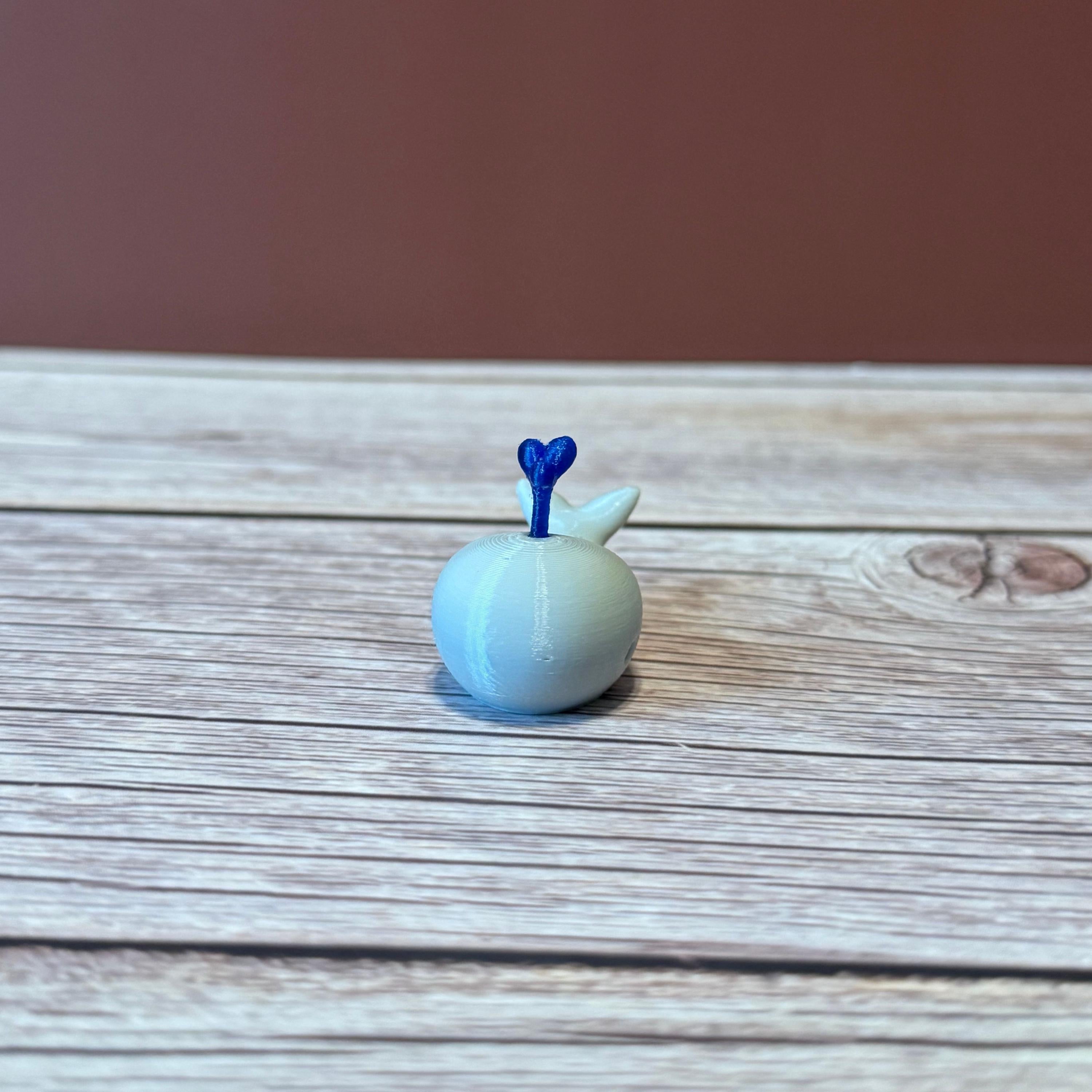 A 3D printed white whale chopstick rest with a space for holding chopsticks, placed on a wooden surface.