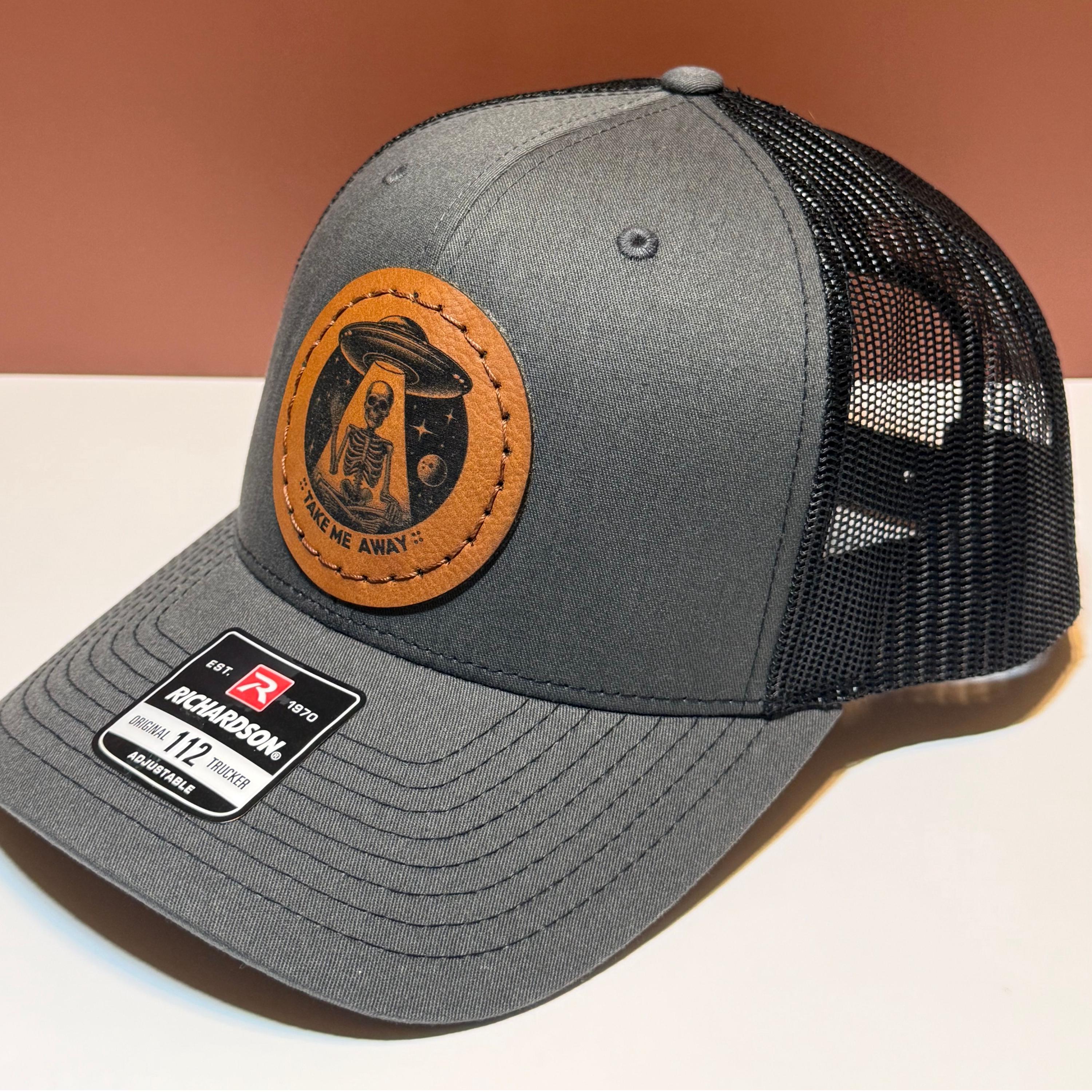 Gray trucker hat with a image of a skeleton and UFO with the phrase 