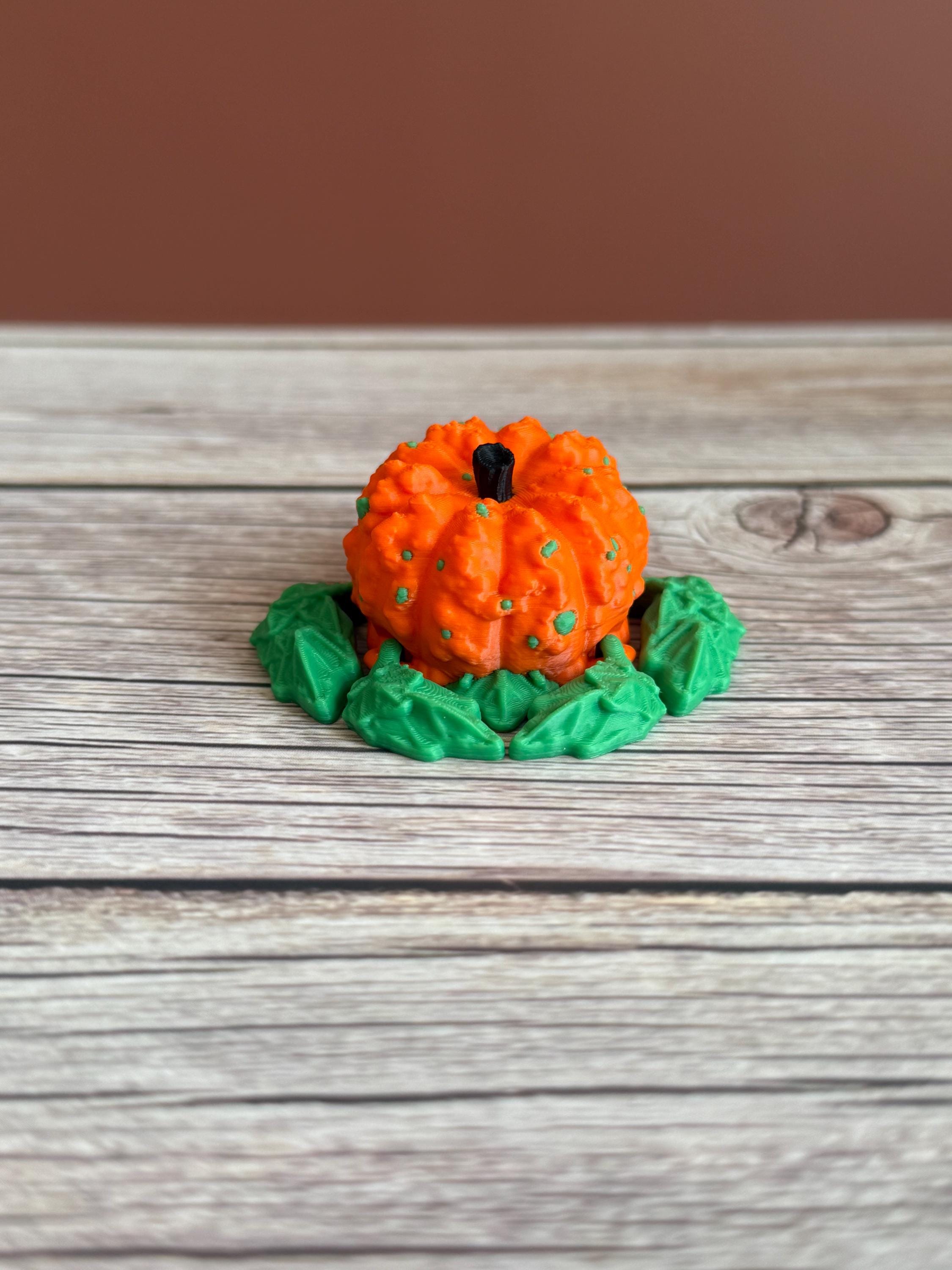 3D printed pumpkin-shaped turtle figure with leaf-like flippers, placed on a wooden surface