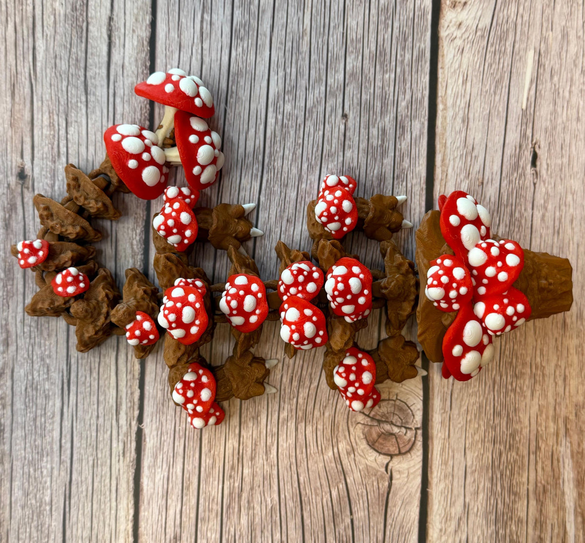 A 12-inch articulated 3D printed dragon with a design resembling a mushroom, with red and white caps on a wooden surface.