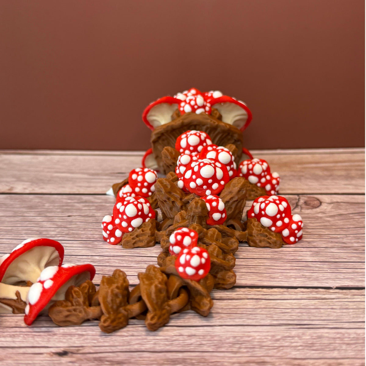 A 12-inch articulated 3D printed dragon with a design resembling a mushroom, with red and white caps on a wooden surface.
