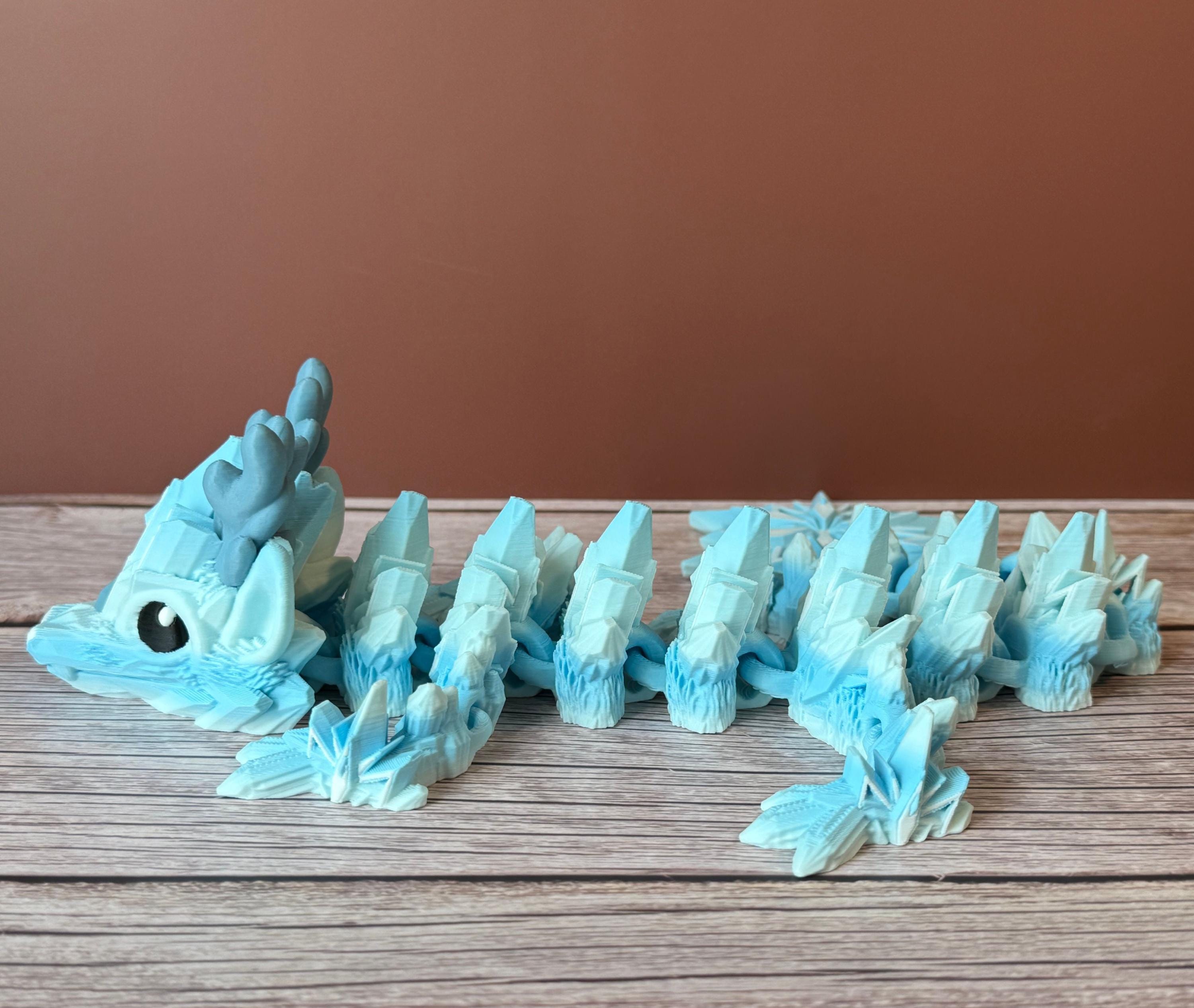 Blue dragon toy featuring a winter themed body with snowflake tail, placed on a wooden surface