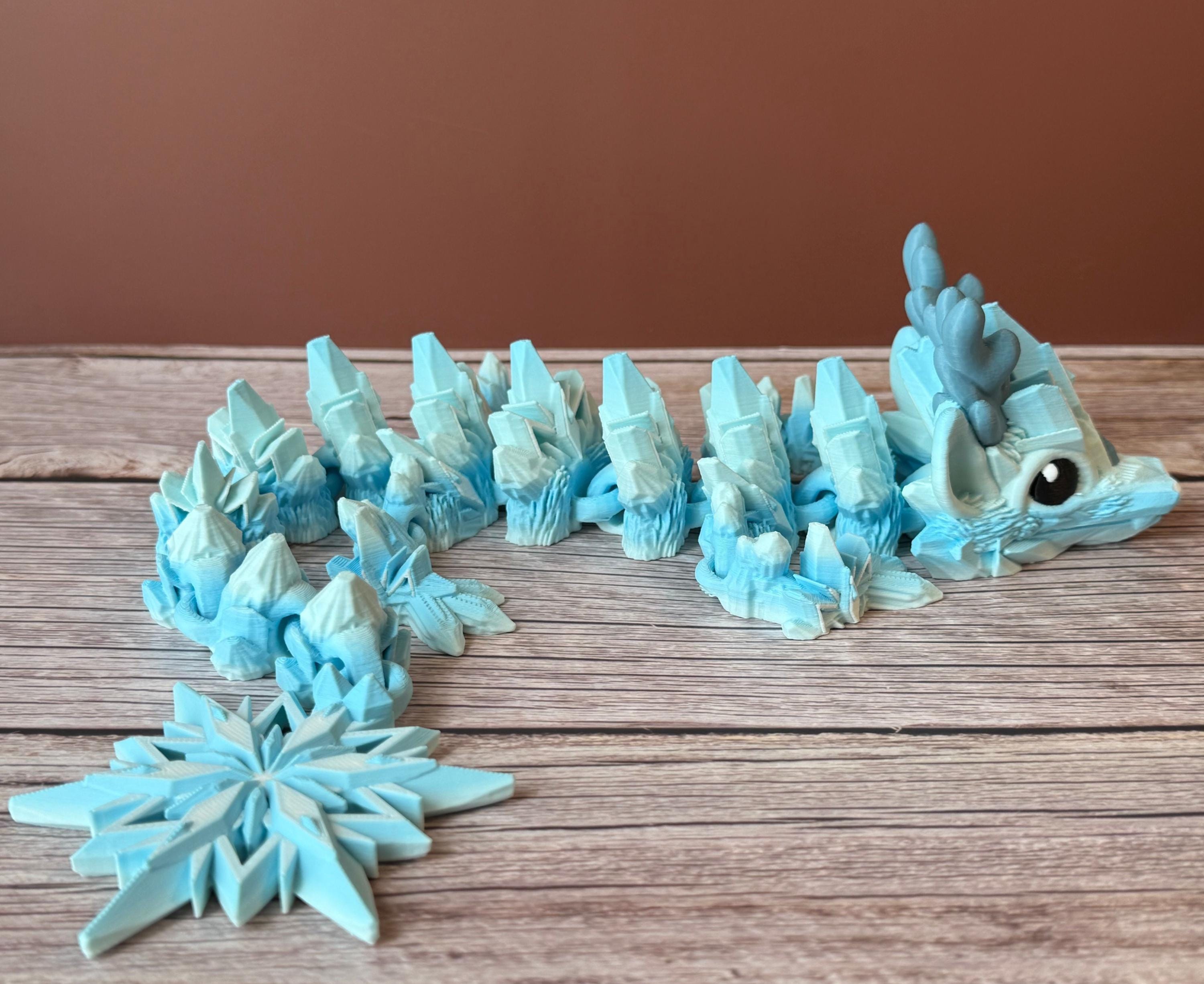Blue dragon toy featuring a winter themed body with snowflake tail, placed on a wooden surface