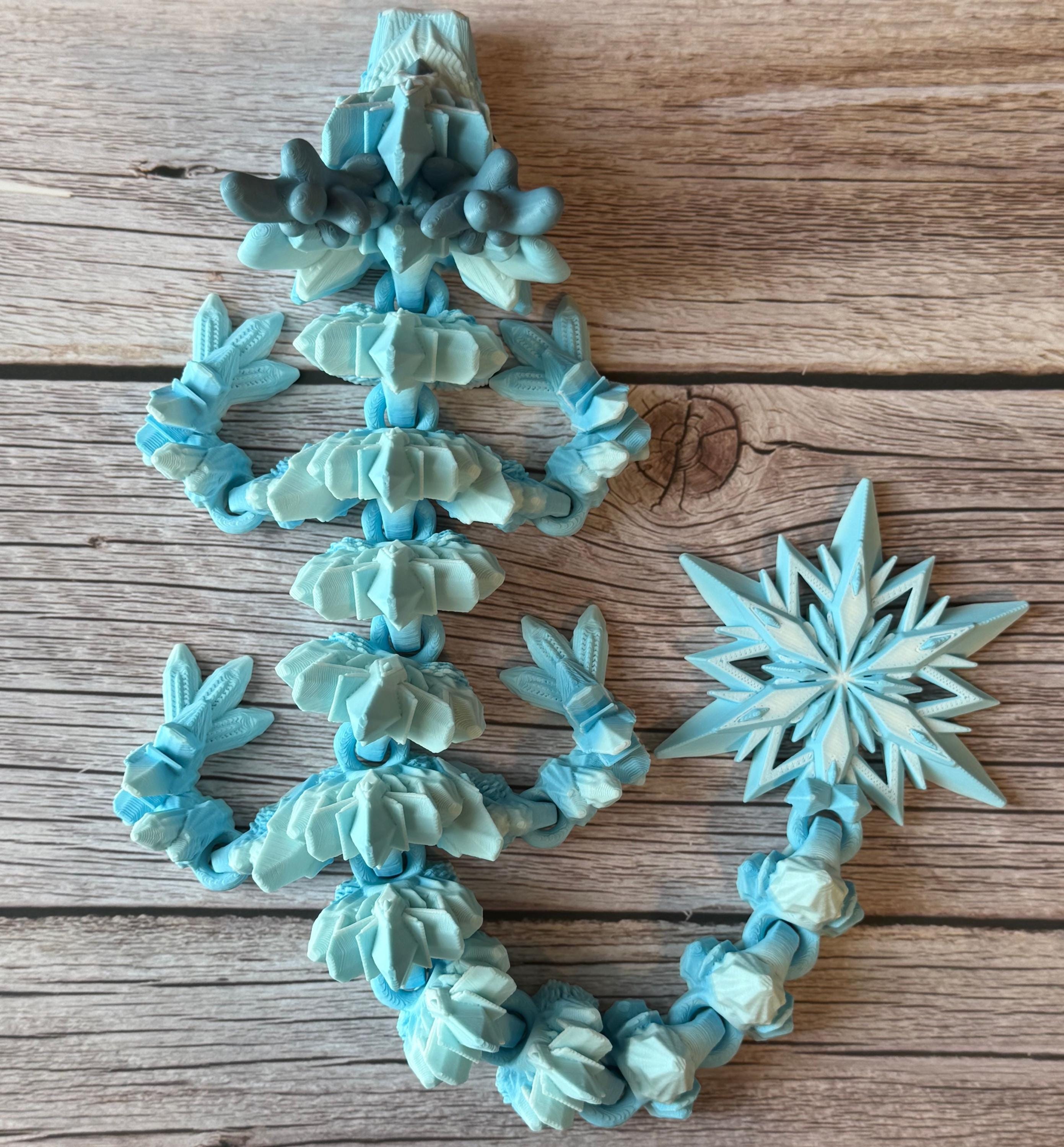 Blue dragon toy featuring a winter themed body with snowflake tail, placed on a wooden surface