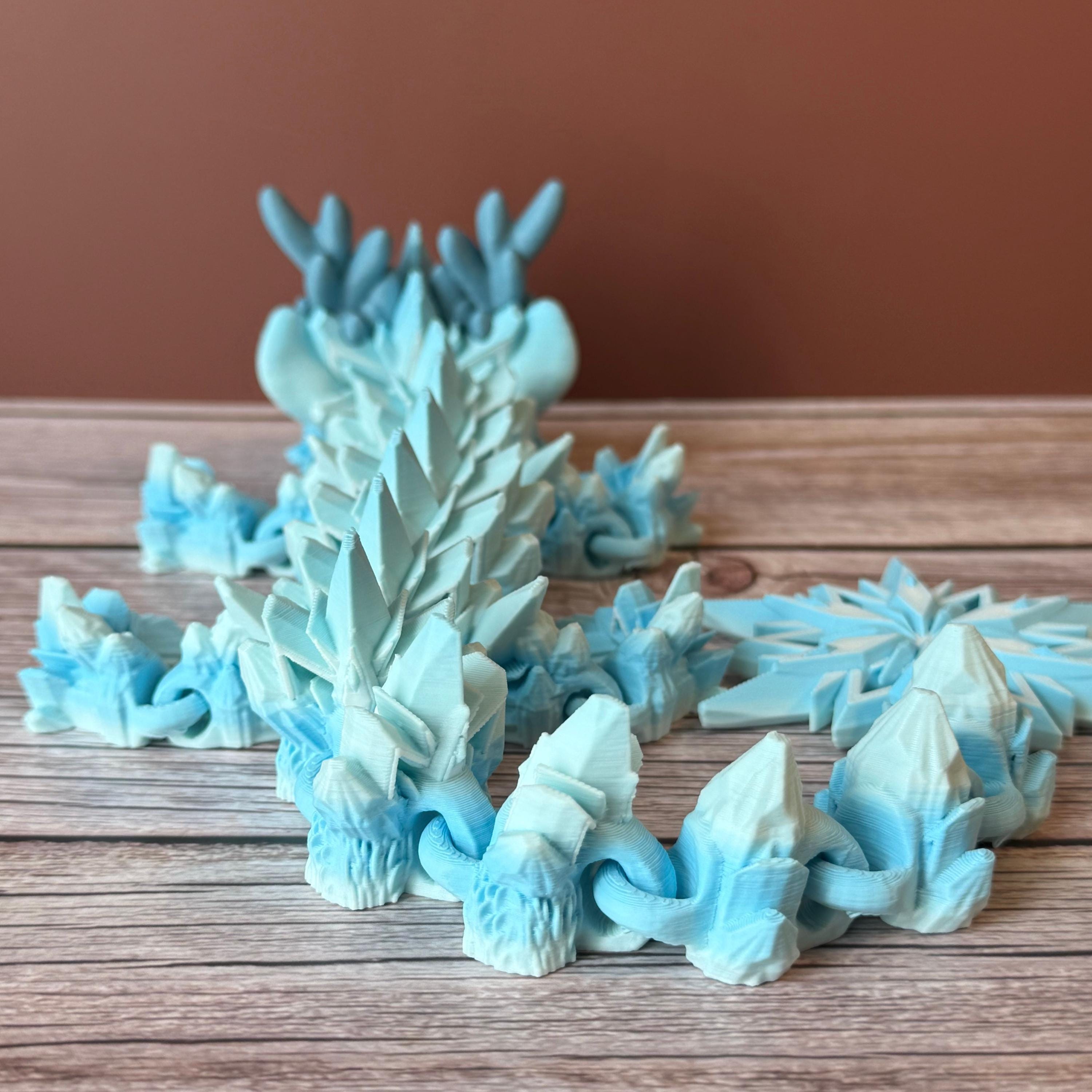 Blue dragon toy featuring a winter themed body with snowflake tail, placed on a wooden surface