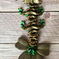 Brown and green 3D printed dragon figure with a clover shaped tail, placed on a wooden surface