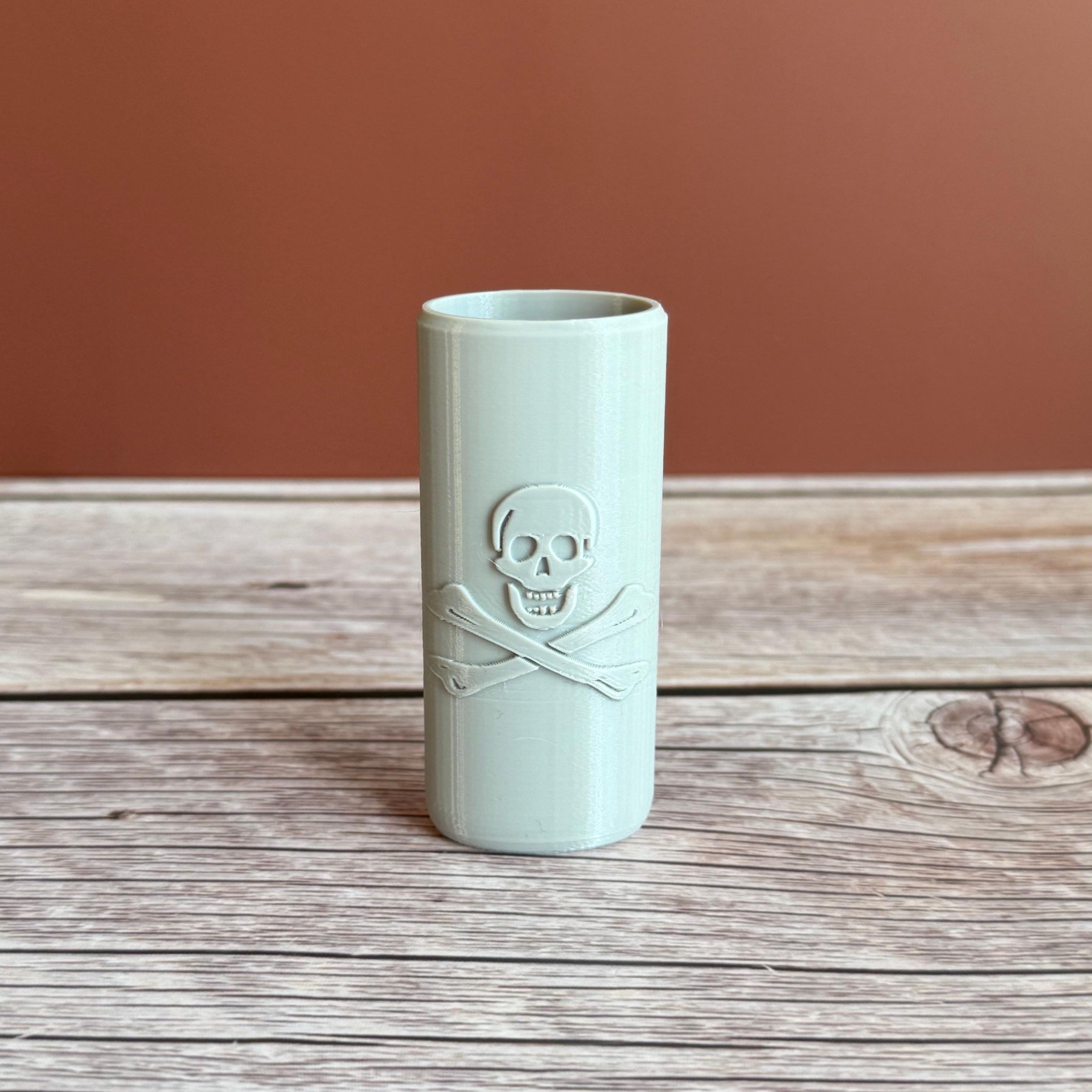 A 3D printed Bic lighter case with Skull and Crossbones design displayed in gray color on wooden surface and brown background