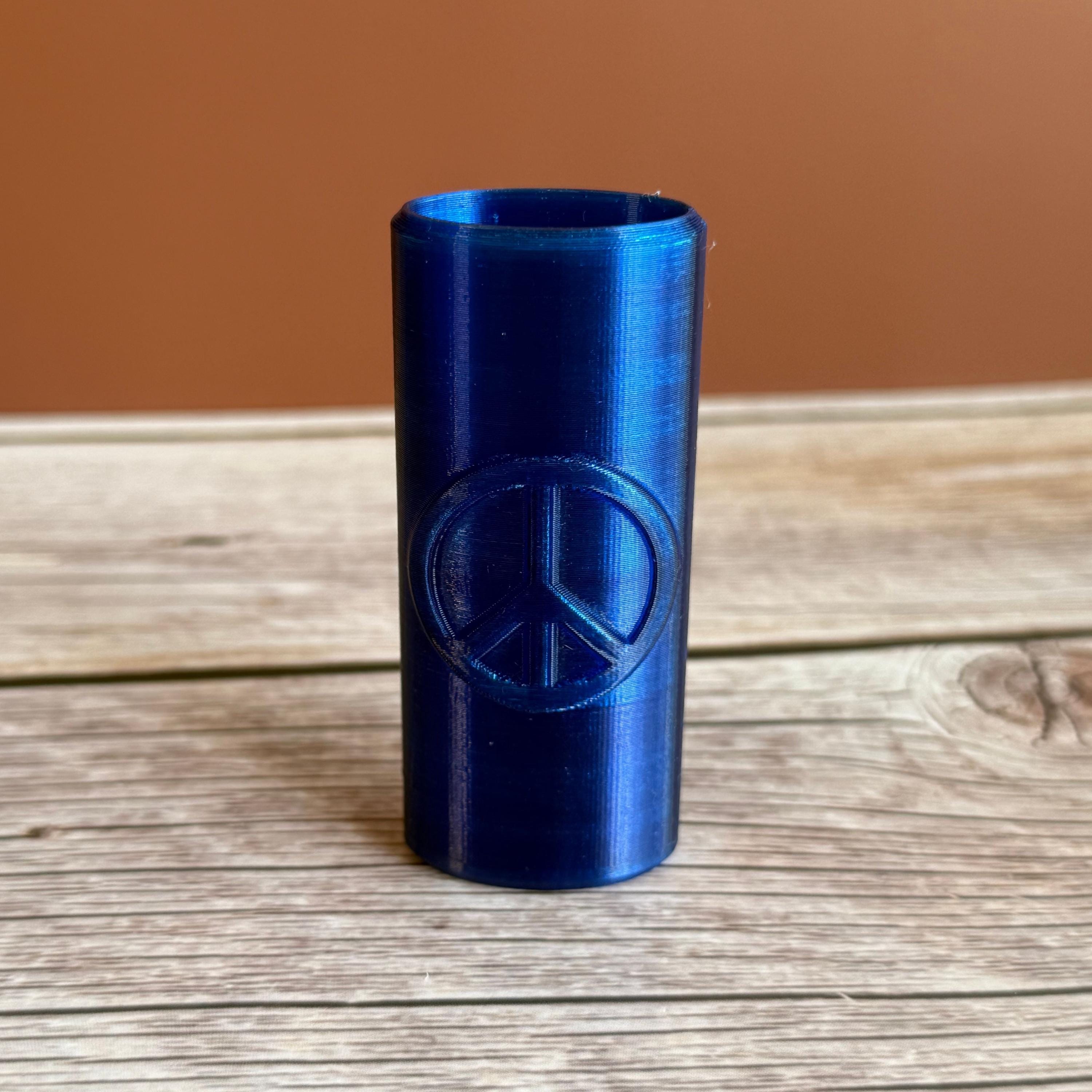 A 3D printed Bic lighter case with Peace sign design displayed in blue color on wooden surface and brown background